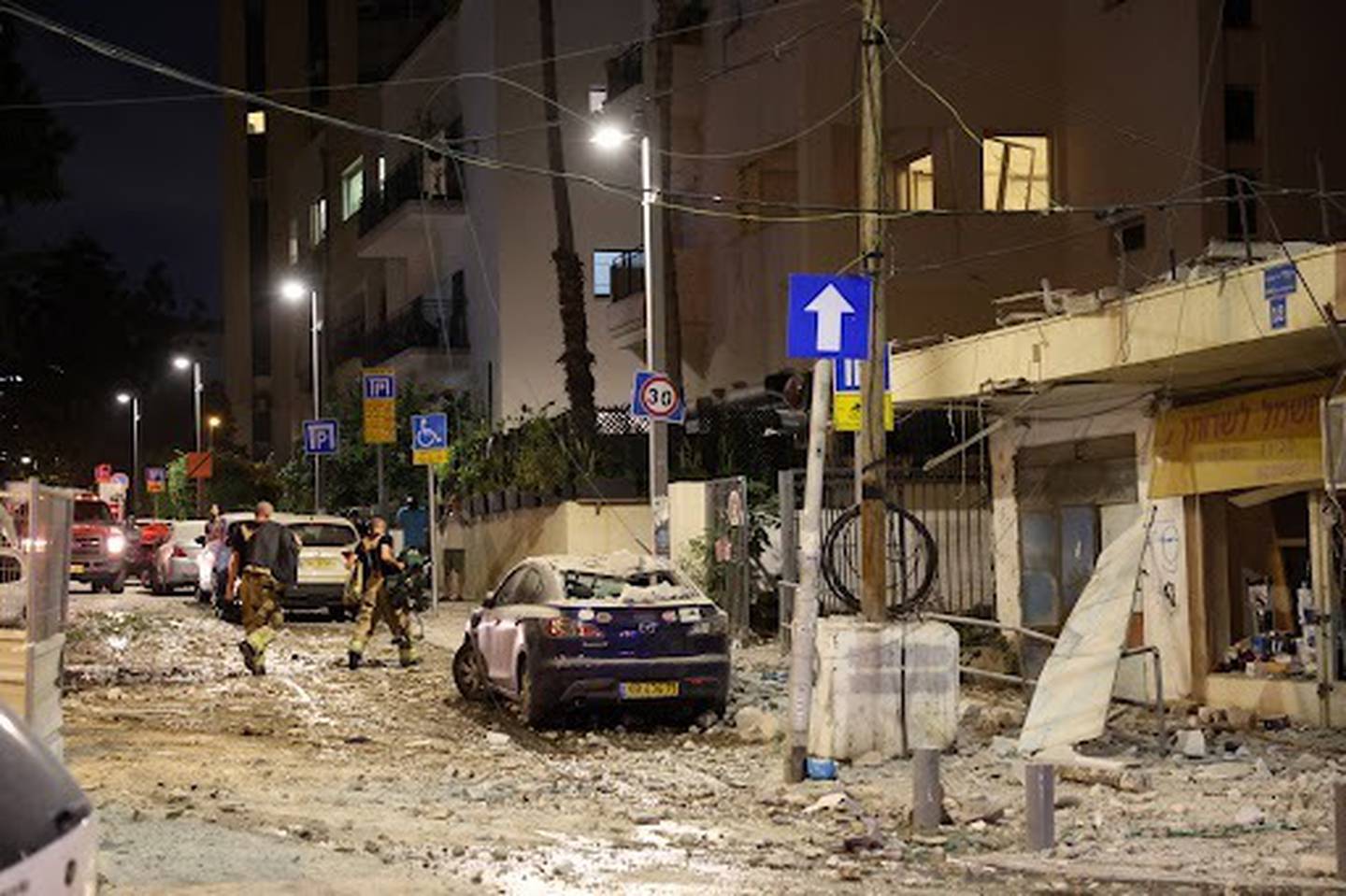 Miembros de las fuerzas de seguridad israelíes caminan entre escombros en Tel-Aviv, luego de que un cohete palestino golpeara la ciudad el sábado.