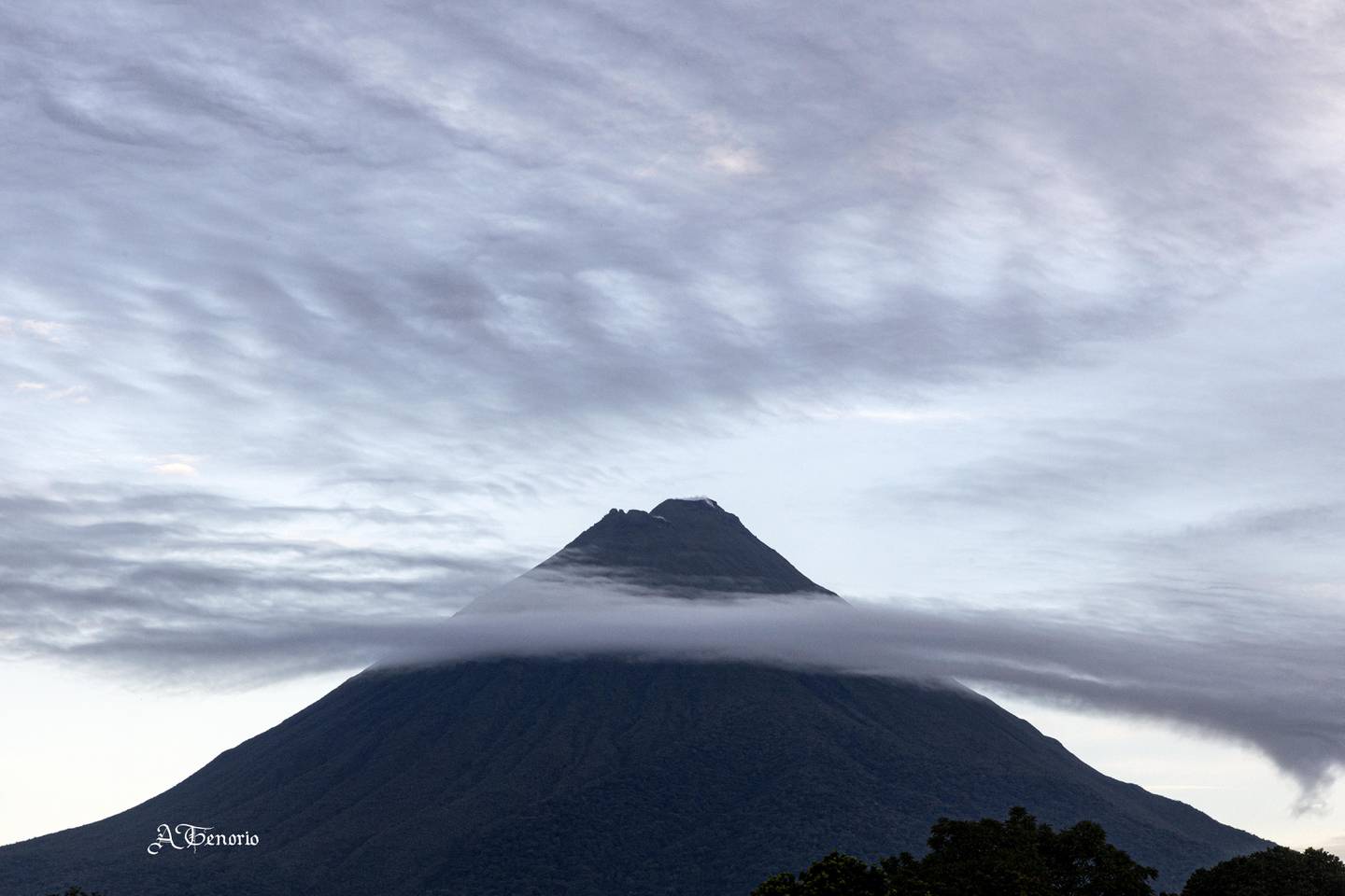 Postal hermosa del volcán Arenal, tomada desde La Fortuna de San Carlos como a las 4:50 de la mañana. Una nube sirve de "velo" para adornar la vista