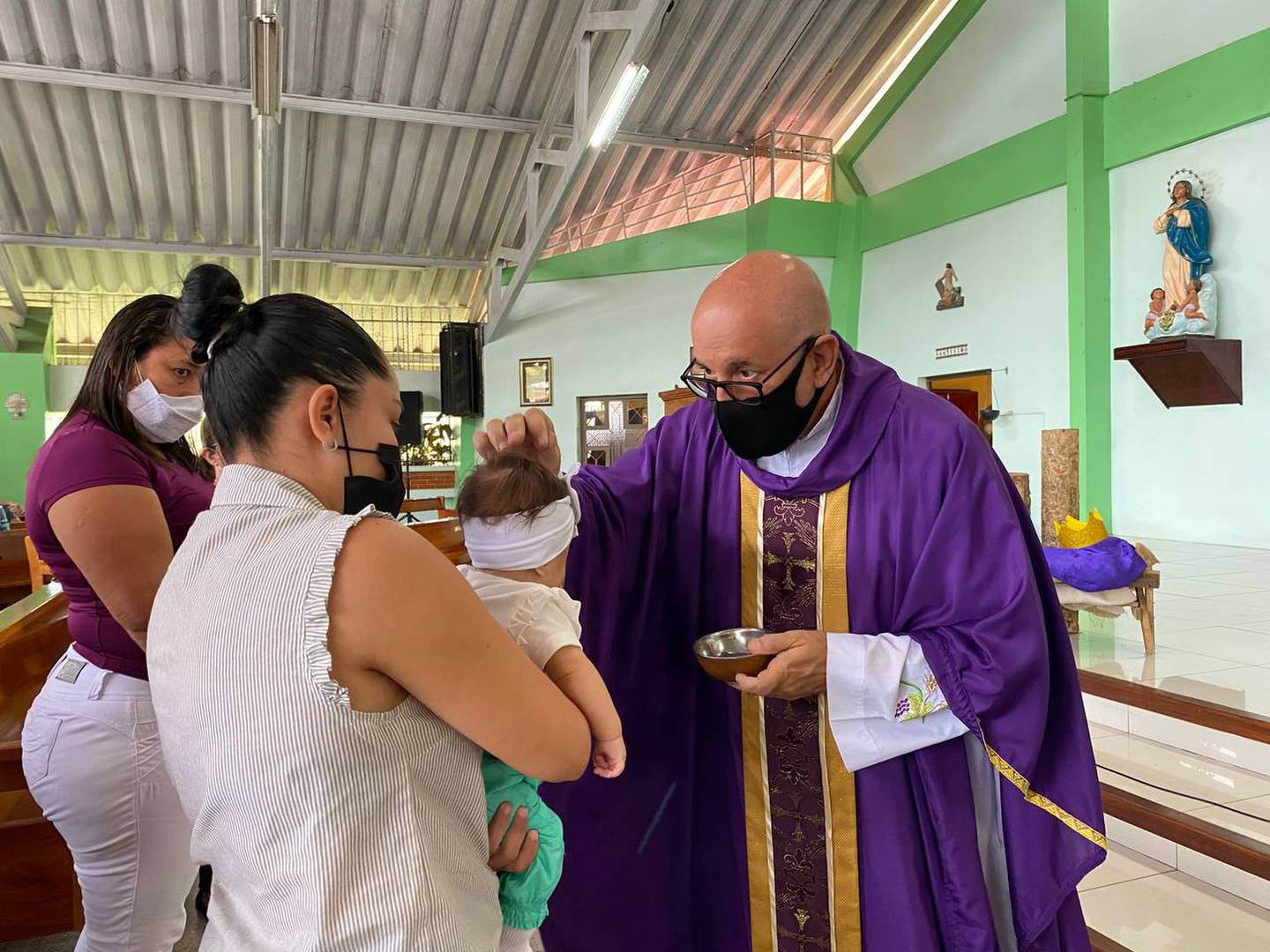 El padre Francisco Trejos de la diócesis de Limón le pone ceniza en la cabeza a un bebito el 2 de marzo, Miércoles de Ceniza 2022