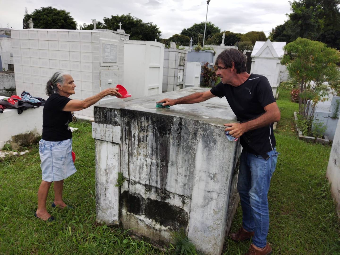 Don Carlos Noguera y su mamá, doña Ligia Ramírez, limpian la tumba en donde está enterrado don Ojedis Ramírez, quien en vida fue el papá y esposo de don Carlos y doña Ligia. La foto fue tomada el 2 de noviembre del 2023 en el cementerio Obreros.