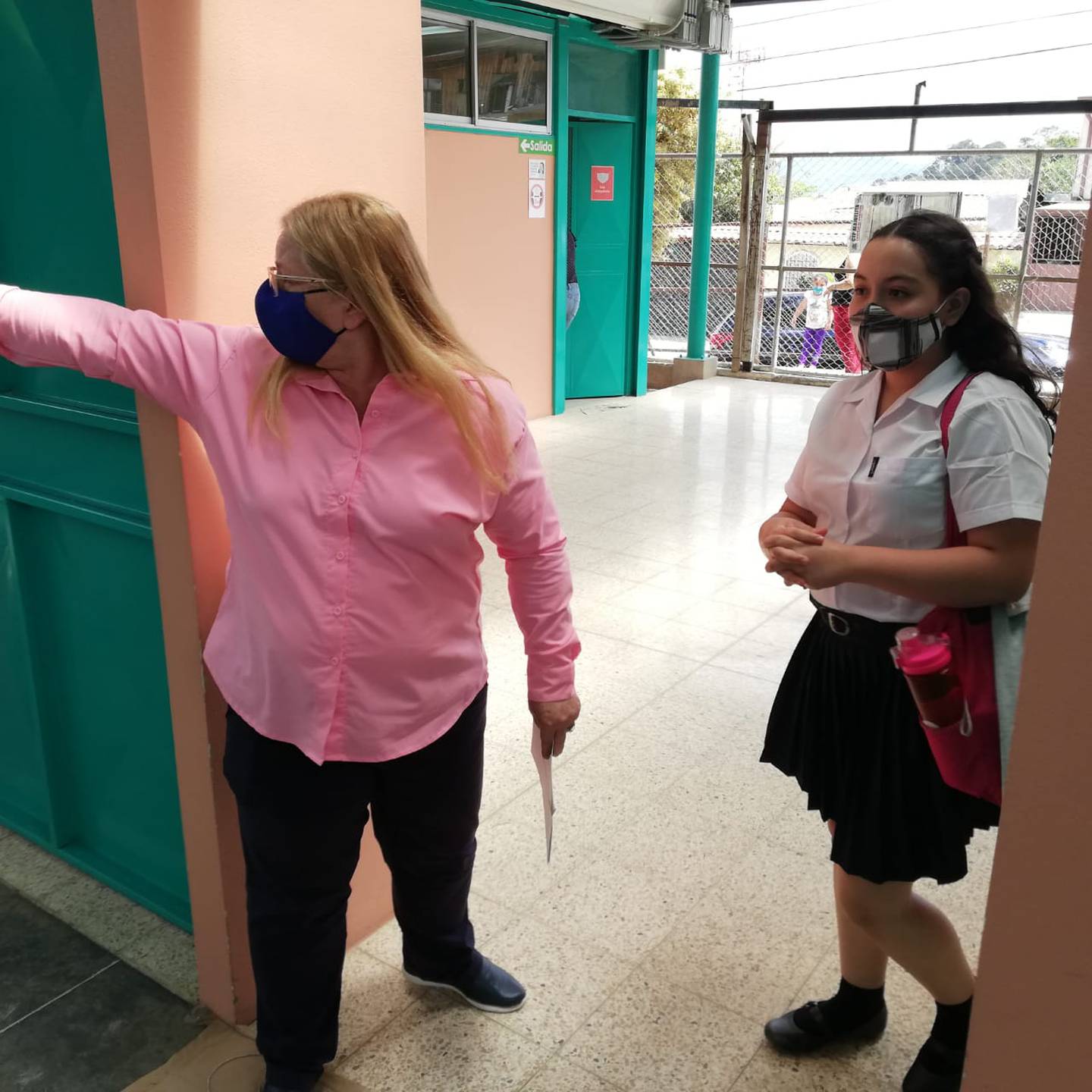La directora de la escuela Ismael Coto de Alajuelita, Nidia Campos Guzmán, le muestra el camino al aula a la estudiante Yoselyn Ramírez de sexto grado.