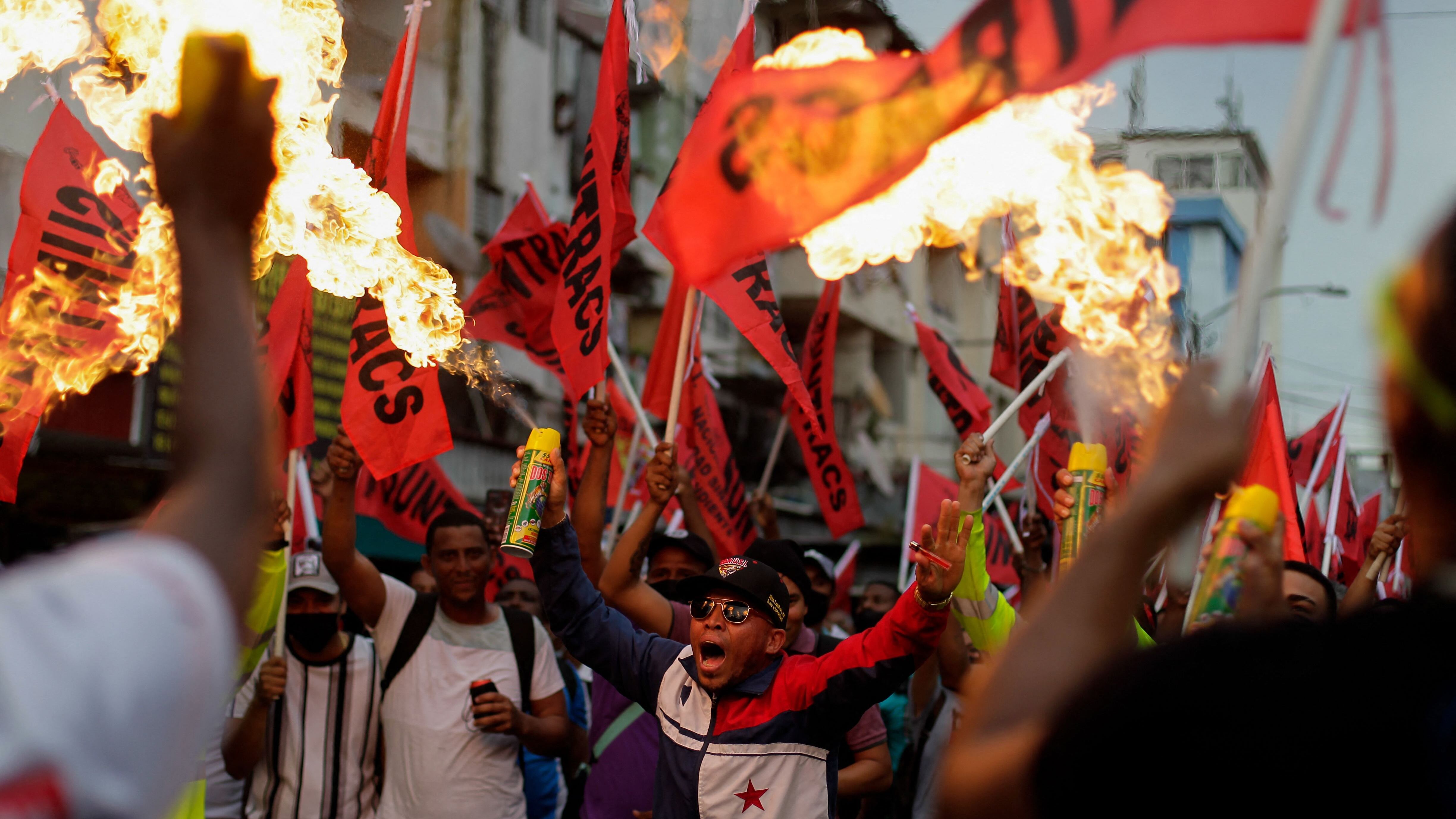 Protesters spray fire during a march against the high cost of food and gasoline in Panama City, on July 12, 2022. - Despite the government's announcement on a solution to the population's petitions, thousands of people marched on Tuesday against rising product prices and corruption in Panama. (Photo by ROGELIO FIGUEROA / AFP)