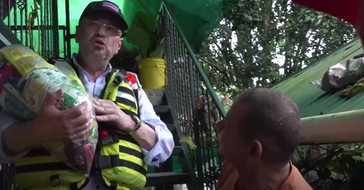El presidente de Costa Rica, Rodrigo Chaves, conversa con un damnificado por lluvias en la zona sur durante una entrega de alimentos.