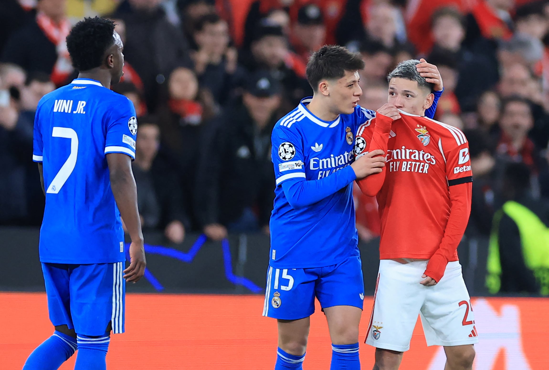 El delantero argentino de SL Benfica #25, Gianluca Prestianni, se cubre la boca mientras discute con el delantero brasileño del Real Madrid #07, Vinicius Junior, quien se quejó de presuntos insultos racistas durante el partido de ida del repechaje de la fase eliminatoria de la Liga de Campeones de la UEFA entre SL Benfica y Real Madrid CF en el Estadio da Luz, en Lisboa, el 17 de febrero de 2026.
La UEFA sancionó al extremo del Benfica, Gianluca Prestianni, con seis partidos el 24 de abril de 2026 tras un incidente polémico en el duelo de la Liga de Campeones contra el Real Madrid en febrero. El organismo rector del fútbol europeo indicó que tomó la decisión de suspender al argentino por conducta discriminatoria (es decir, homofóbica), con tres de esos partidos sujetos a un período de prueba de dos años.
(Foto de PATRICIA DE MELO MOREIRA / AFP)