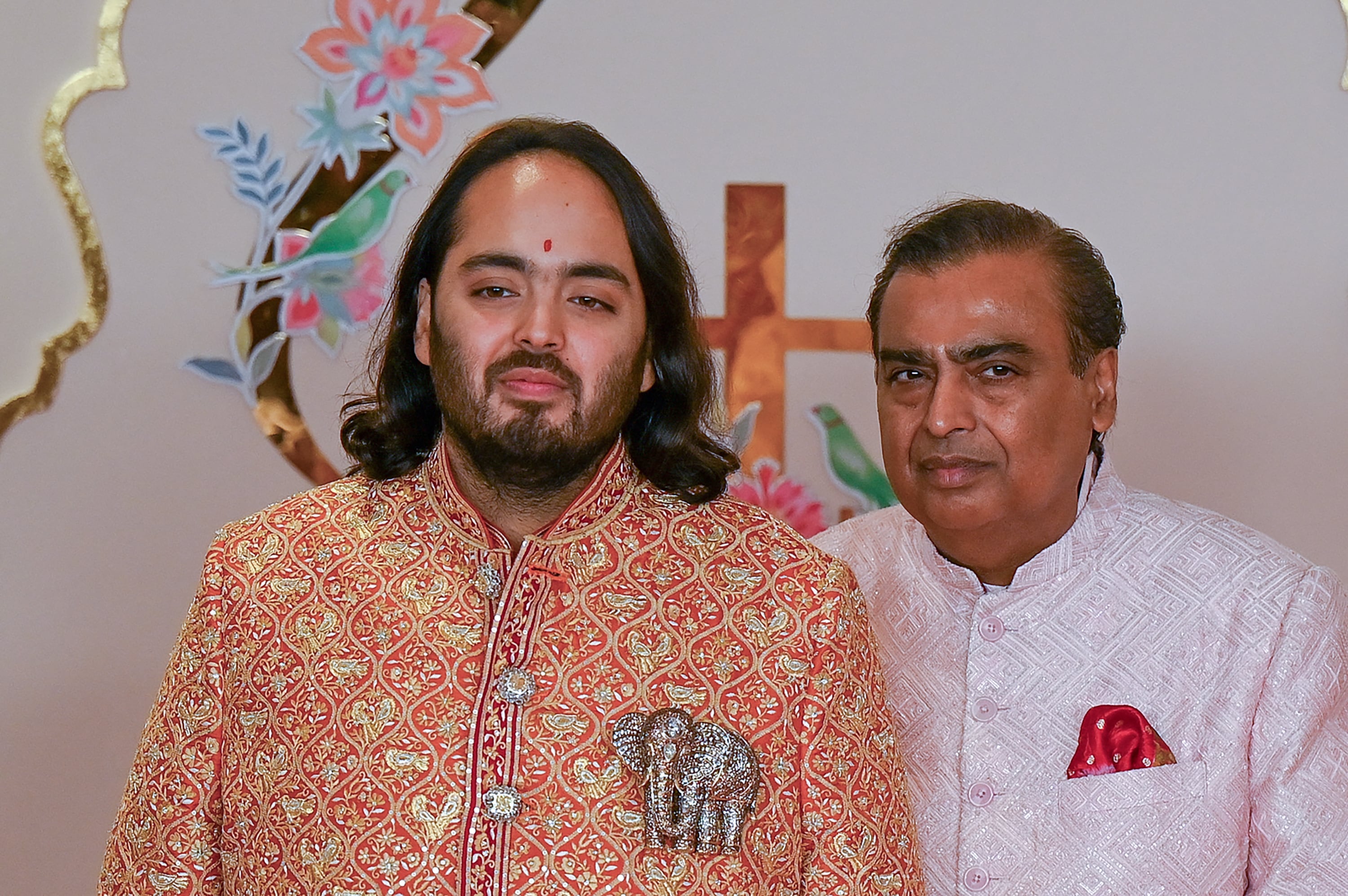 El magnate multimillonario y presidente de Reliance Industries Mukesh Ambani posa para fotografías antes de la ceremonia de boda de su hijo Anant Ambani (izq).