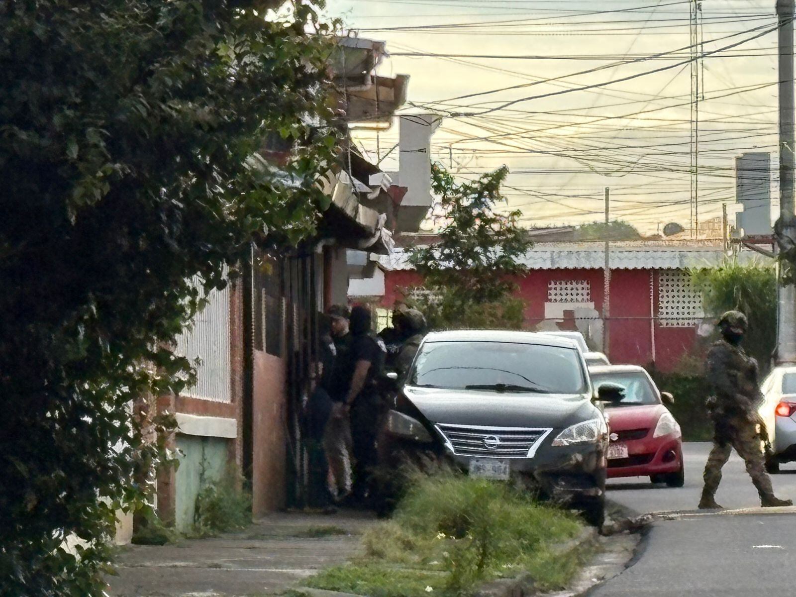 Una calle en un barrio residencial. Automóviles. Agentes del OIJ.