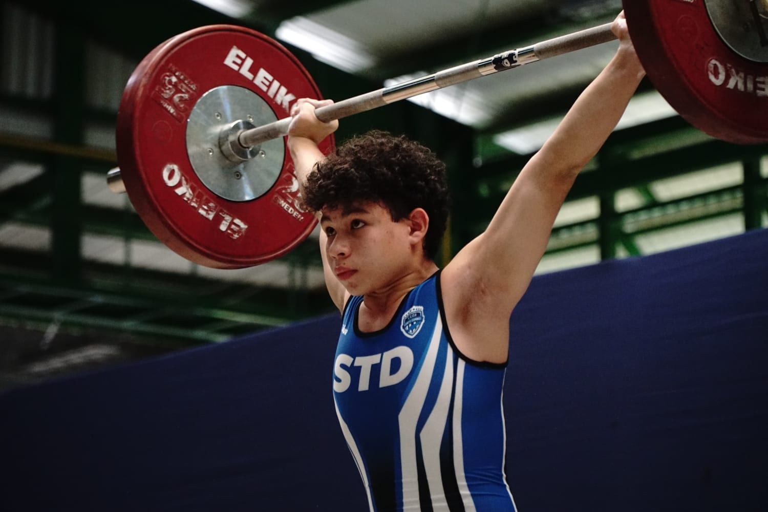 En la categoría juvenil masculina 56 kg, Santiago Lazo Retana, de Santo Domingo y bajo la guía de Ricardo Martínez, brilló con una actuación histórica: levantó 76 kg en arranque y 90 kg en envión para un total de 166 kg, suficientes para romper el récord nacional y quedarse con las tres primeras medallas de oro de estas justas.
