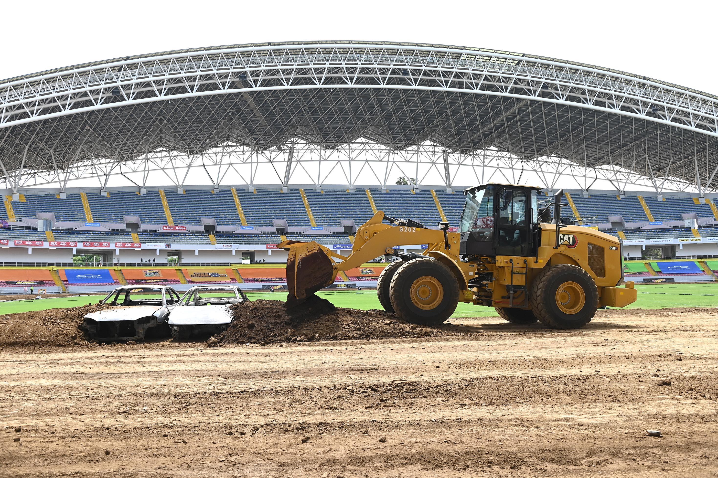 25 de abril del 2025. Estadio Nacional, La Sabana. 10:00 hrs. Preparativos para el show HotWheels Monster Trucks Glow and Fire en la gramilla del Estadio Nacional. Maquinaria pesada realiza movimientos de tierra creando las rampas que los pilotos de monster trucks usarán durante los diferentes shows que ofreceran los días viernes, sábado y domingo de abril. En la foto: Algunos pilotos fueron entrevistados y se documentaron detalles de los vehículos y de los trabajos que realiza la maquinaria pesada. El Danny CR posa para la foto. Foto: Albert Marín. para la Teja.