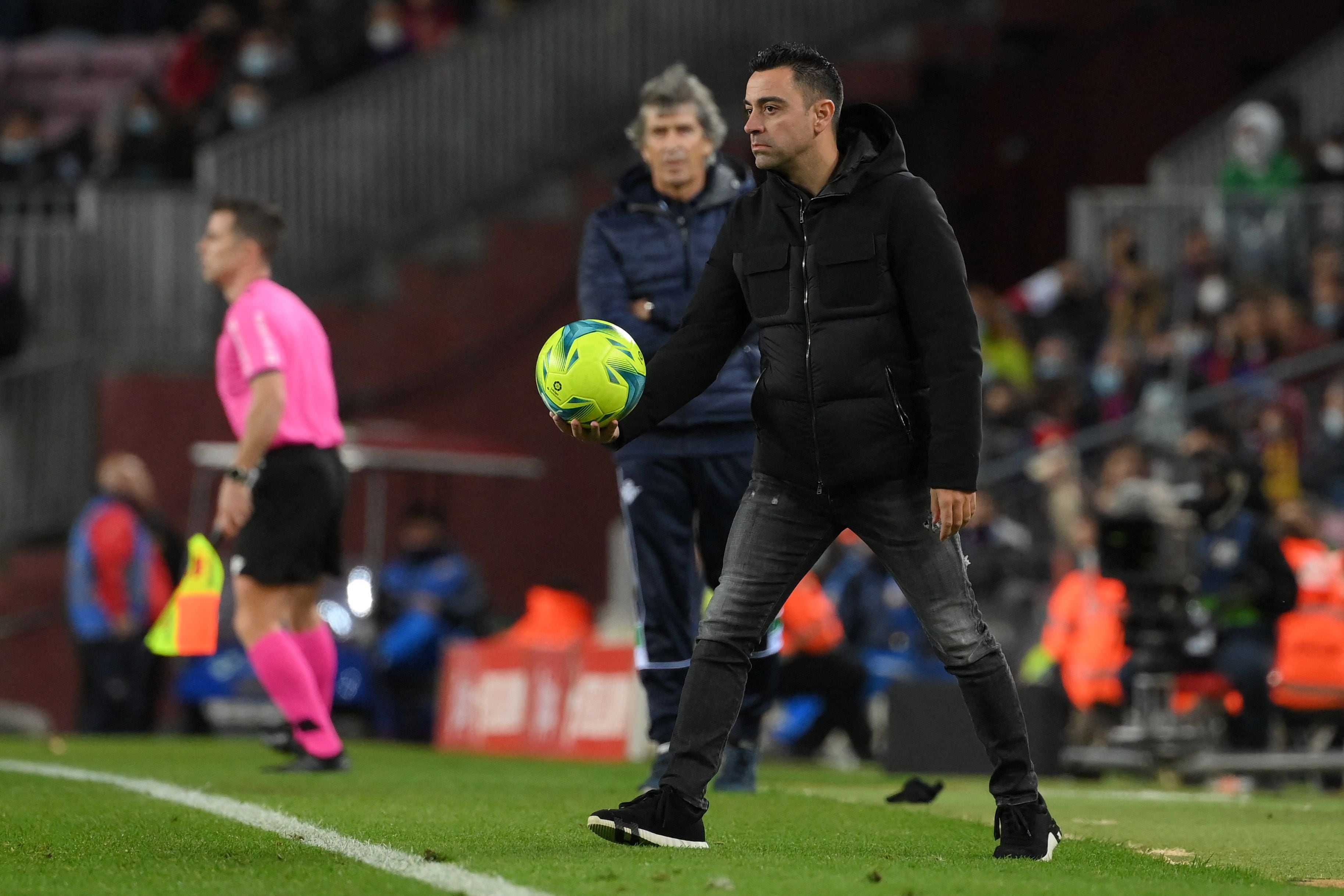 El técnico Xavi Hernández toma el balón durante la derrota del Barcelona ante el Real Betis. AFP