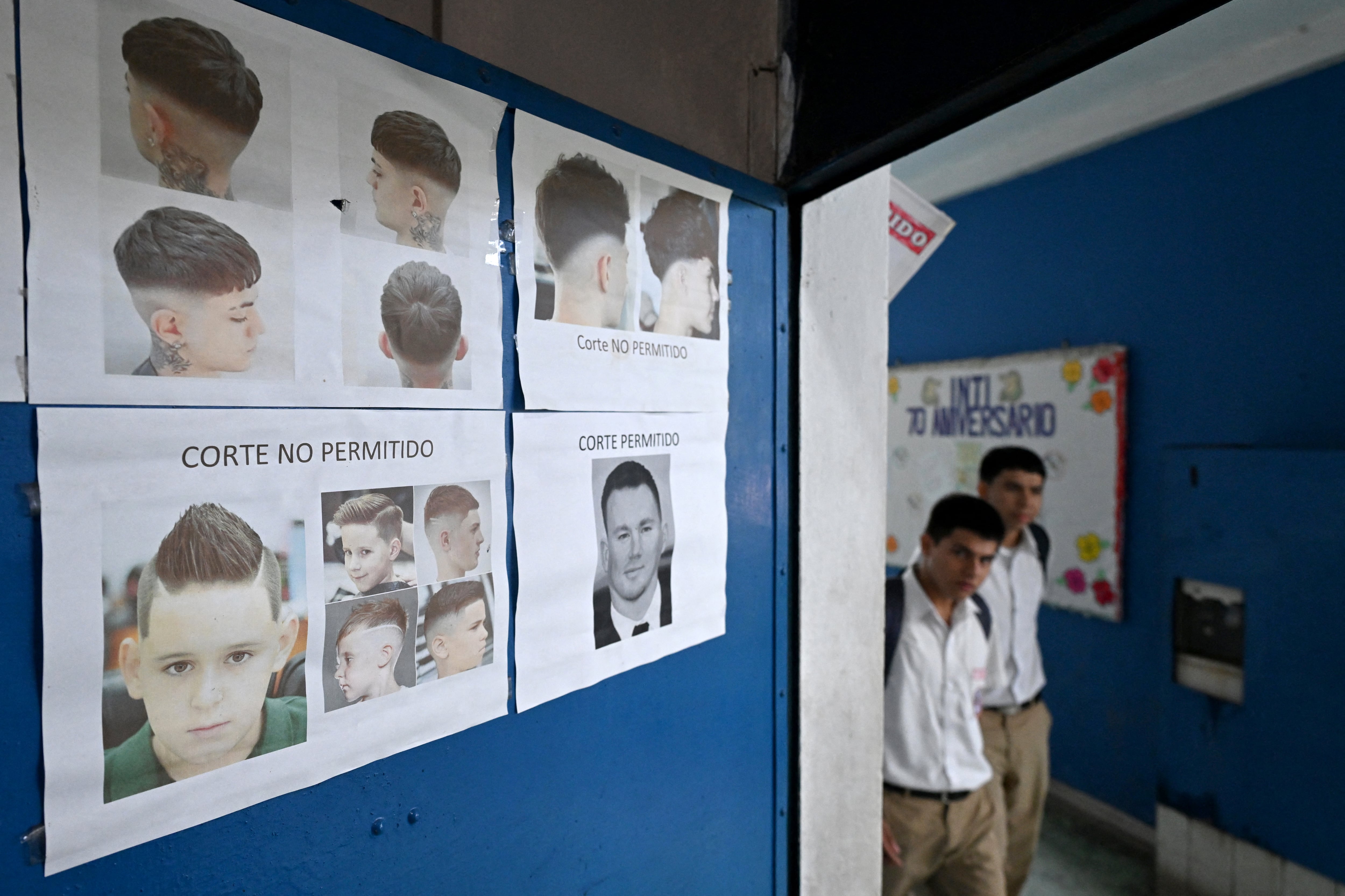También pegaron los ejemplos de los peinados que no permitirán en las escuelas y colegios de El Salvador. (Photo by Marvin RECINOS / AFP)