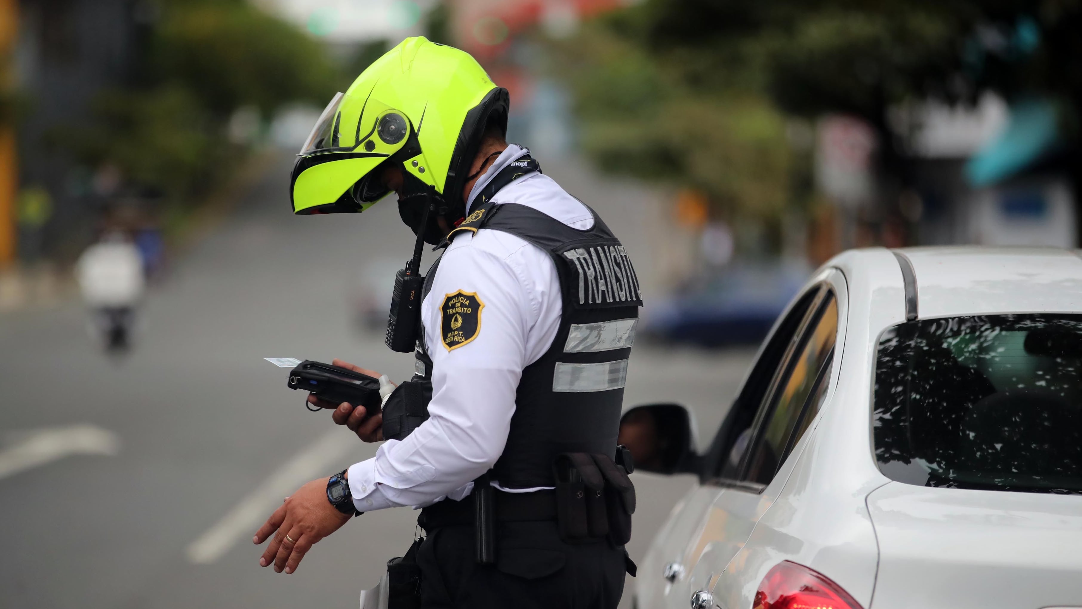 Oficial de la Policía de Tránsito en Costa Rica verifica documentos de un conductor detenido en un operativo de control en carretera.