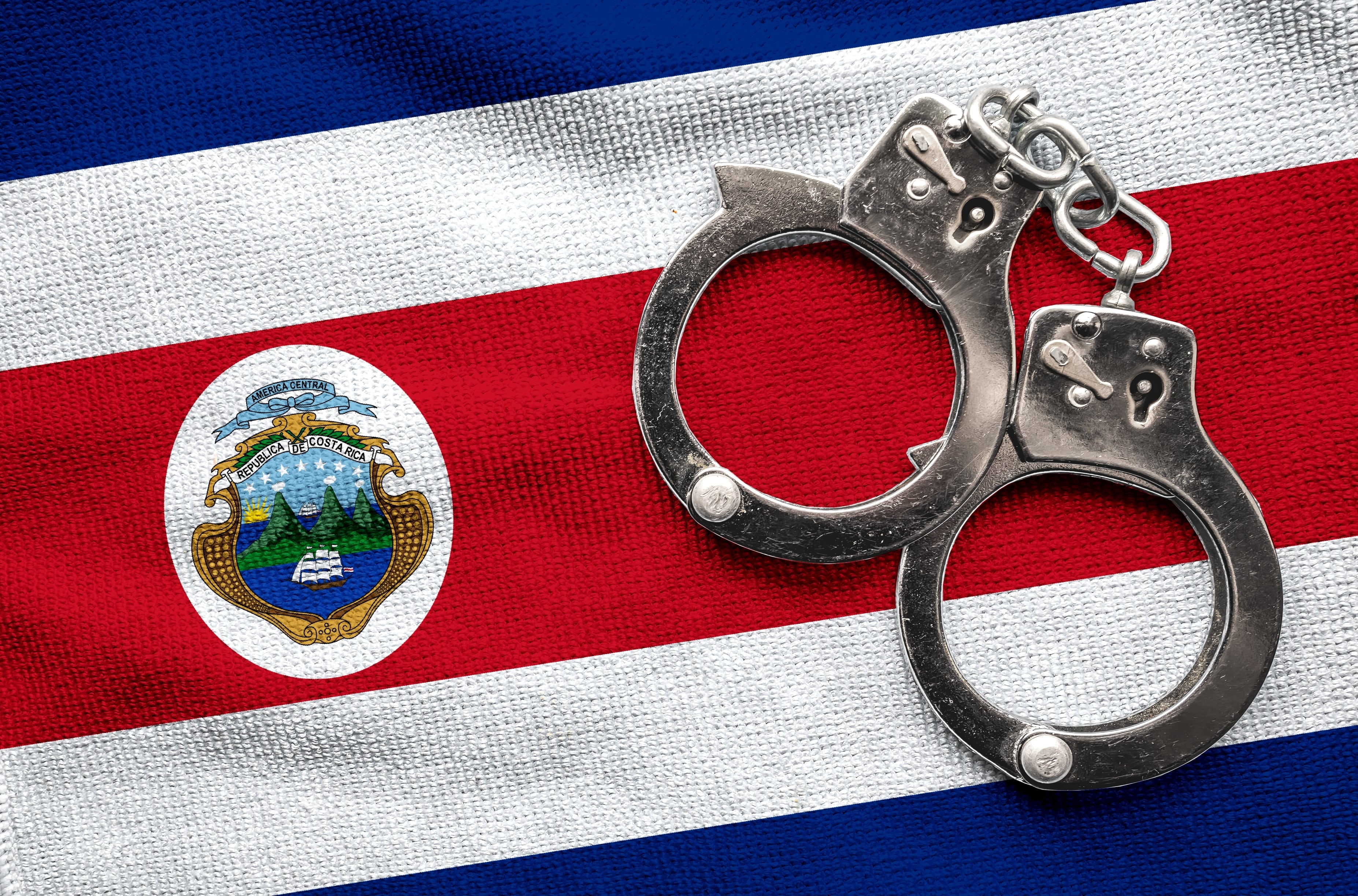 Inseguridad, crisis de violencia, crimen organizado en Costa Rica, esposas sobre bandera de Costa Rica, seguridad ciudadana
