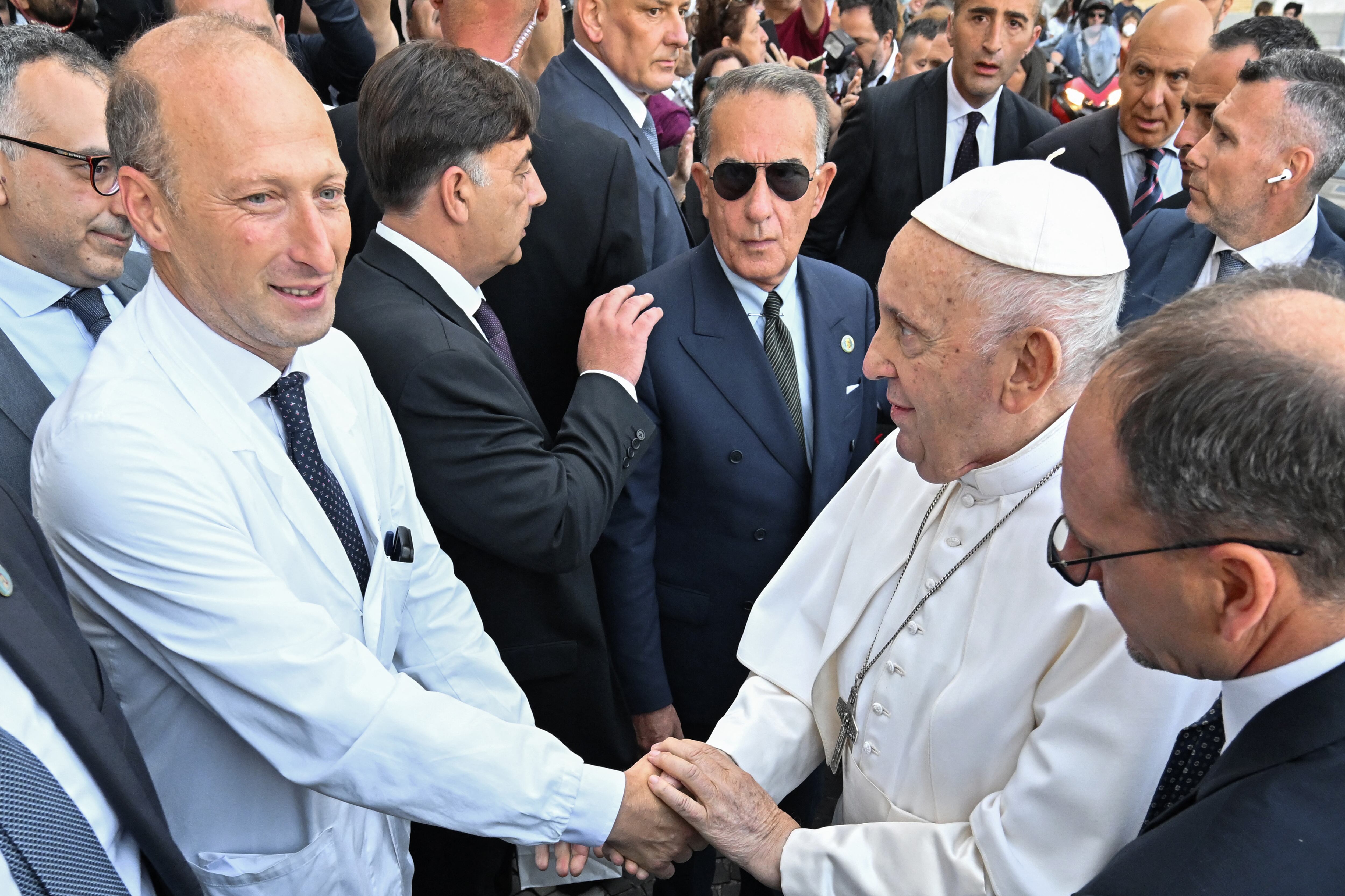 Pope Francis (R) shakes hand with Director of the department of Abdominal and Endocrine Metabolic Medical and Surgical Sciences at the Gemelli hospital, professor Sergio Alfieri, as he leaves after being discharged from the Gemelli hospital in Rome on June 16, 2023, where he underwent abdominal surgery last week. (Photo by Alberto PIZZOLI / AFP)