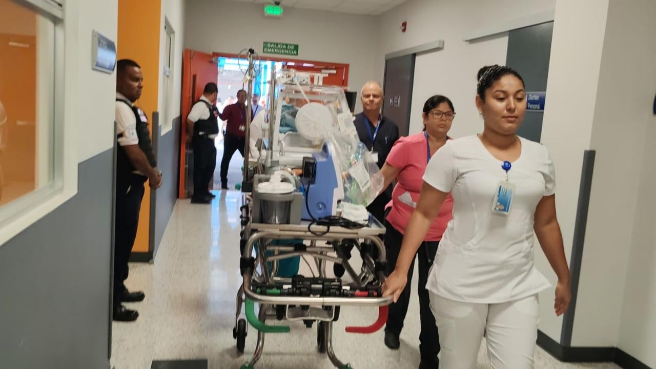 Enfermera lleva incubadora con bebé por pasillo hospitalario