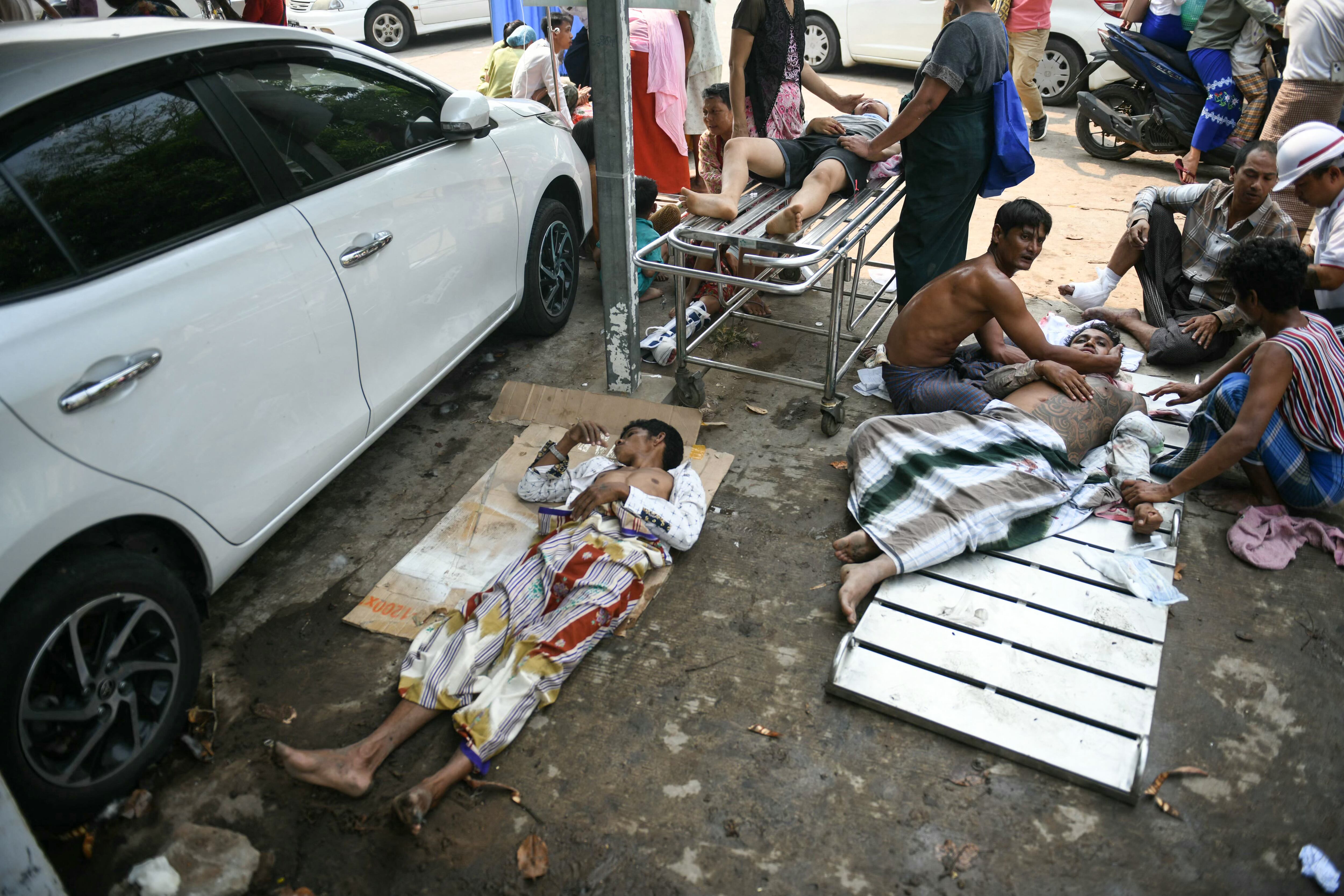 Survivors wait to receive medical attention as they lie on the ground of the compound of a hospital in Naypyidaw on March 28, 2025, after an earthquake in central Myanmar. A powerful earthquake rocked central Myanmar on March 28, buckling roads in capital Naypyidaw, damaging buildings and forcing people to flee into the streets in neighbouring Thailand. (Photo by Sai Aung MAIN / AFP)