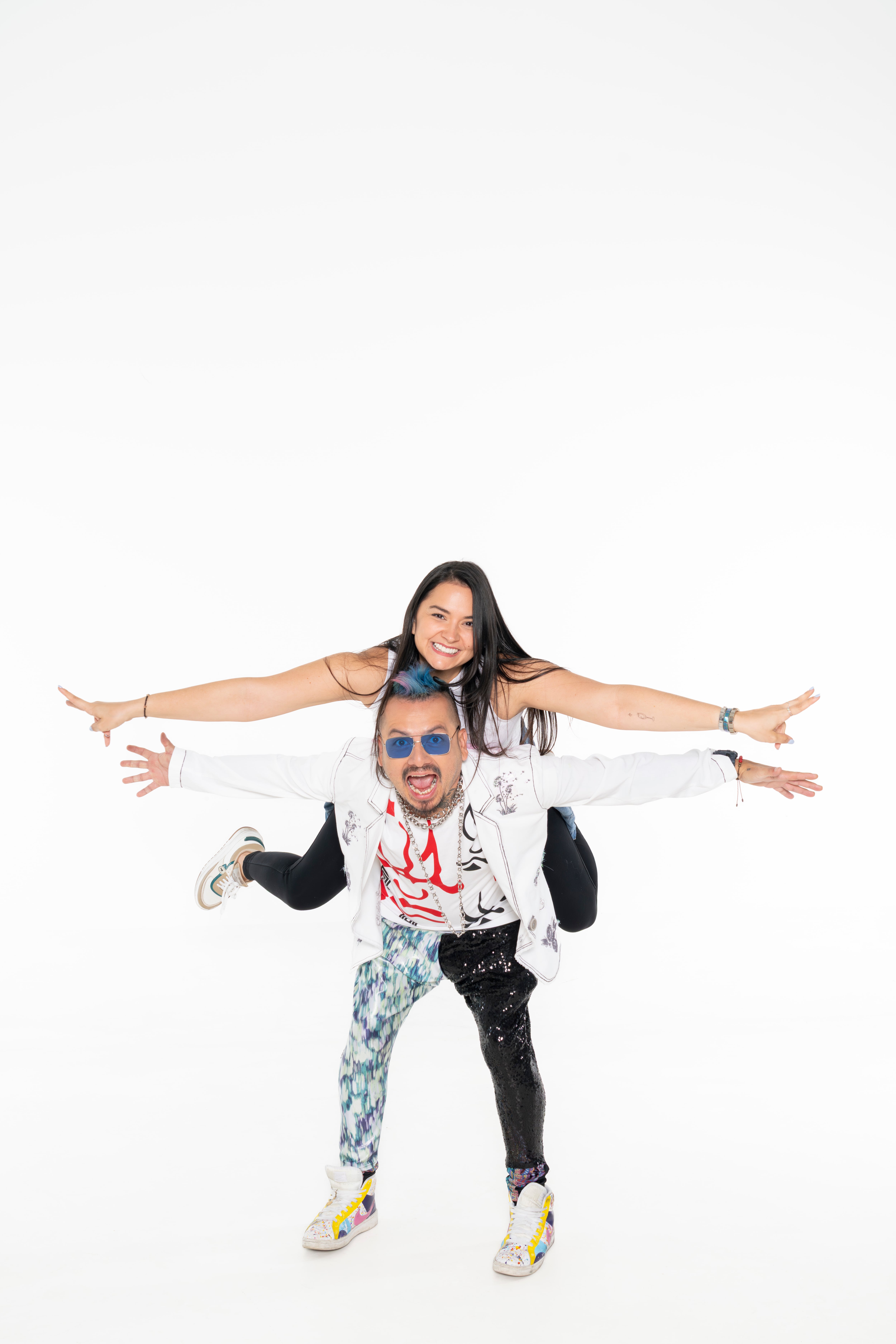 Luisga Loría en sesión de fotos, usa una chaqueta blanca. Carga sobre la espalda a su novia Mónica Barboza.