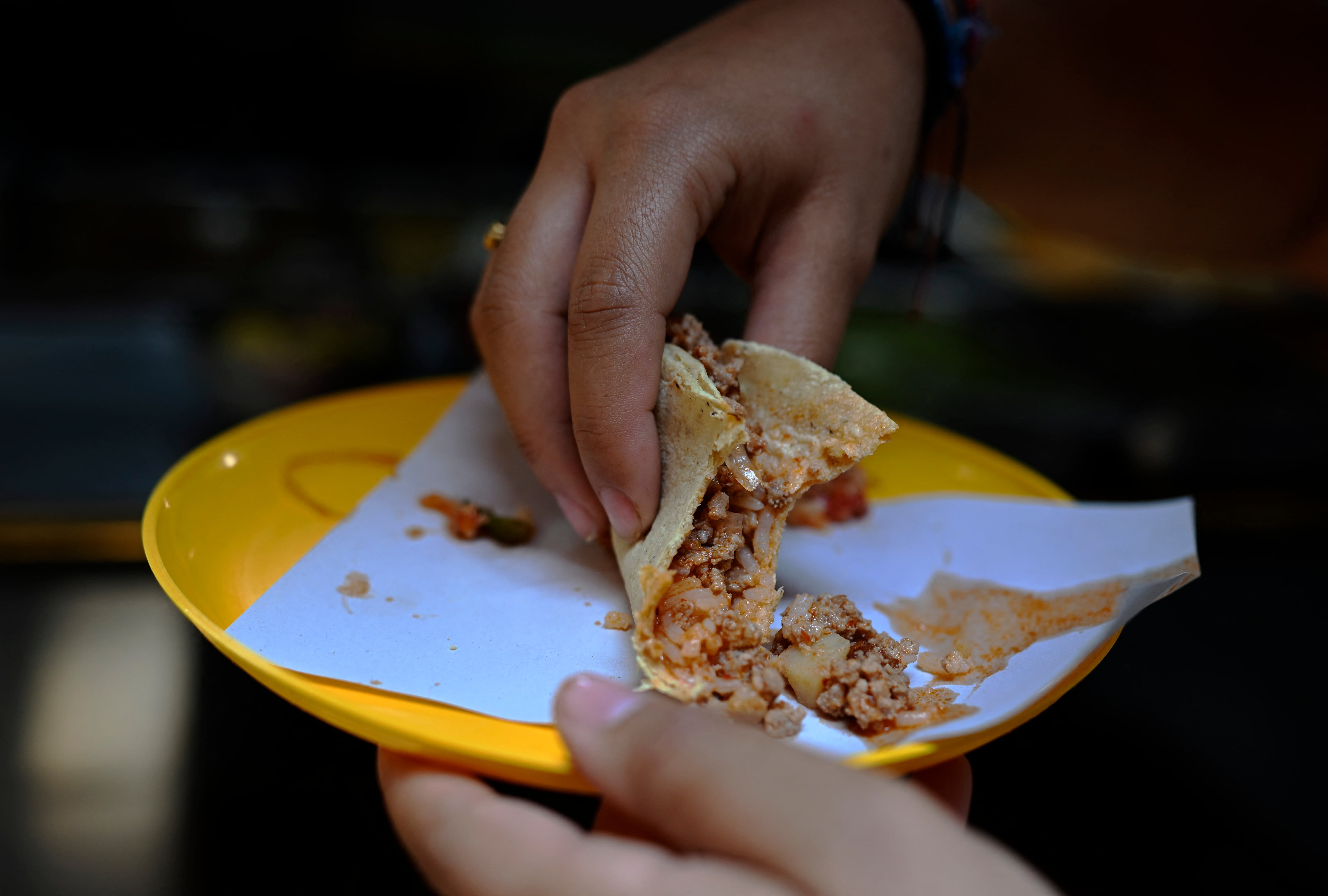 Una mujer come un taco en un puesto de comida callejera en el barrio Roma de Ciudad de México el 8 de mayo de 2025.
