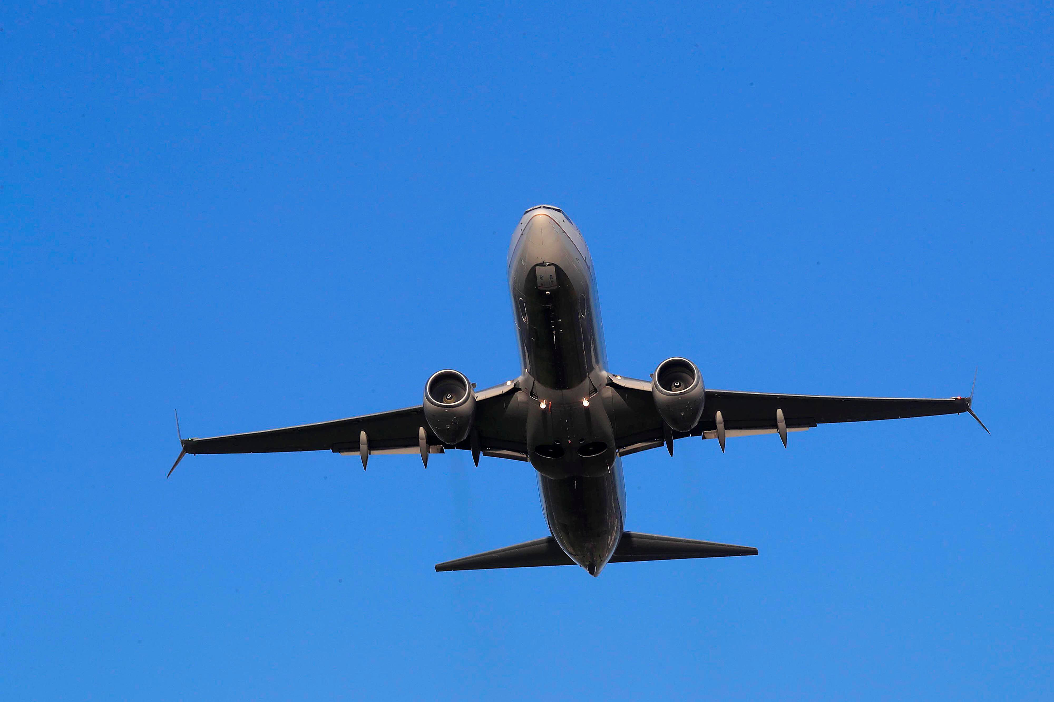 Un avión en pleno vuelo con el cielo azul de fondo.
