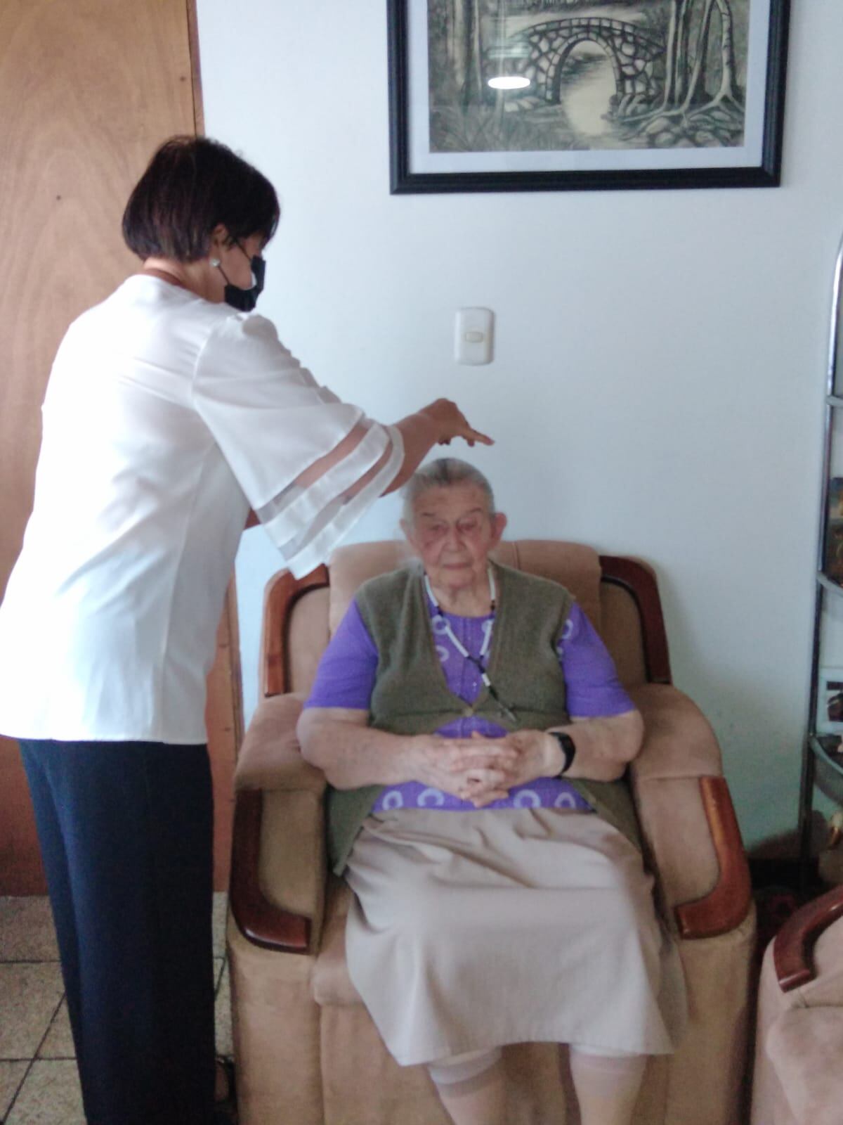 Anabelle Molina González, ministra de la comunión en Ciudad Quesada, le impone ceniza en la cabeza a doña Marta Bolaños