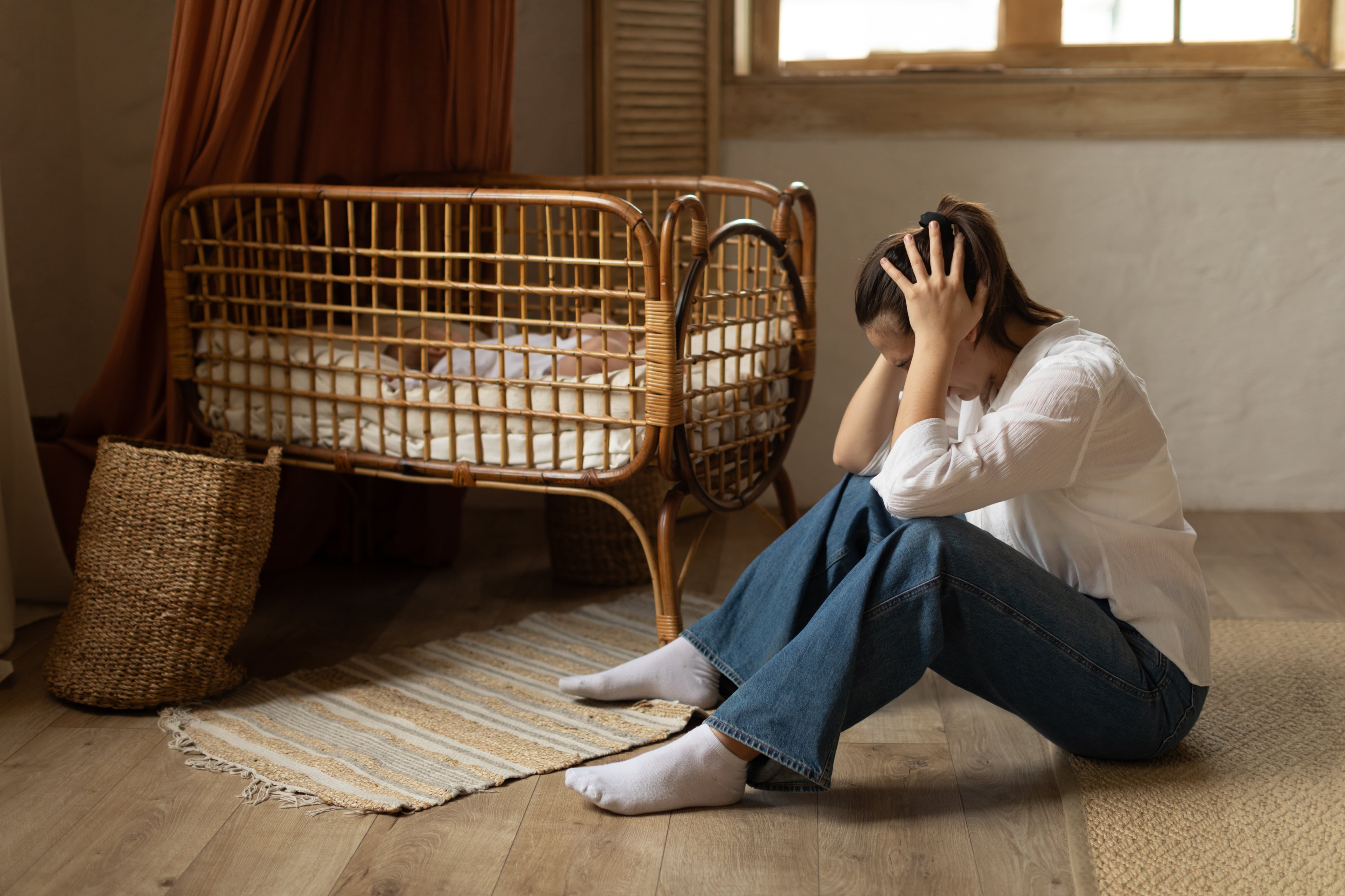 Una mujer llorando al lado de la cuna donde está su recién nacido.