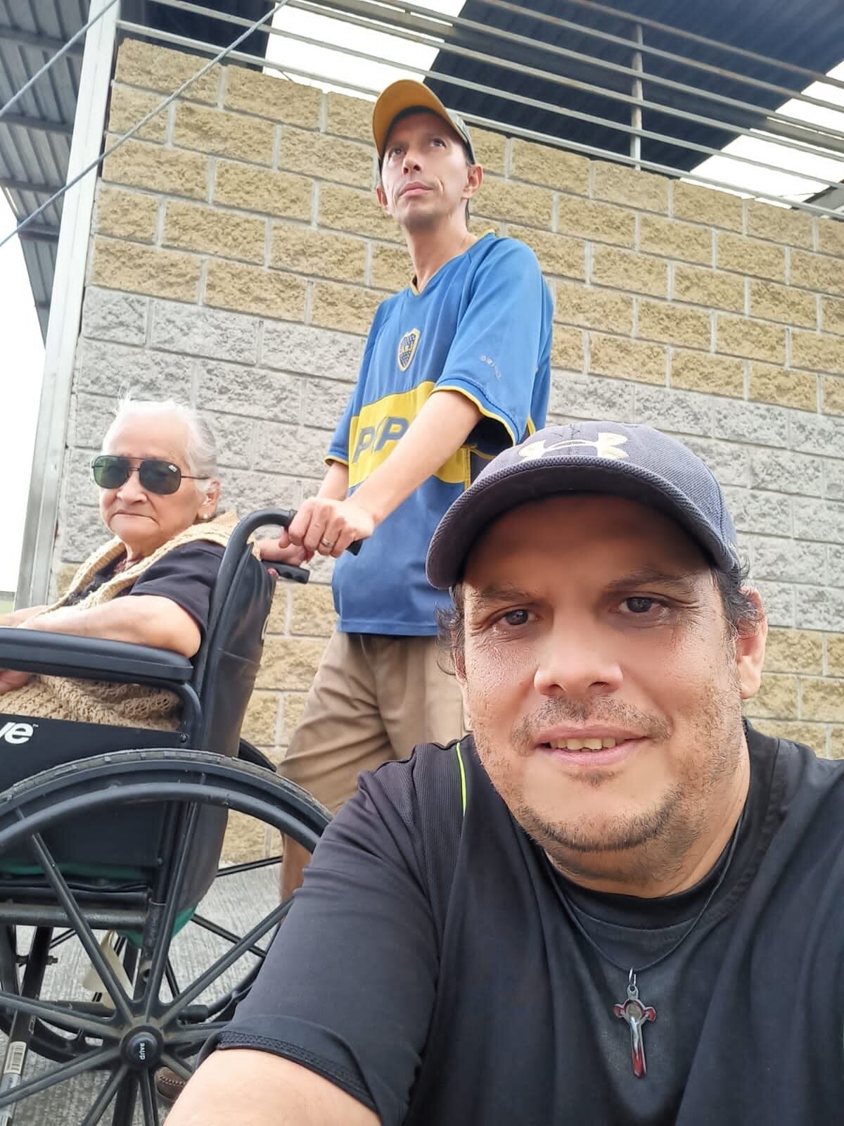 Luis Artavia empuja la silla de ruedas de su mamá, doña Ilma Porras Ávila y les acompaña Jovel Artavia, hermano.