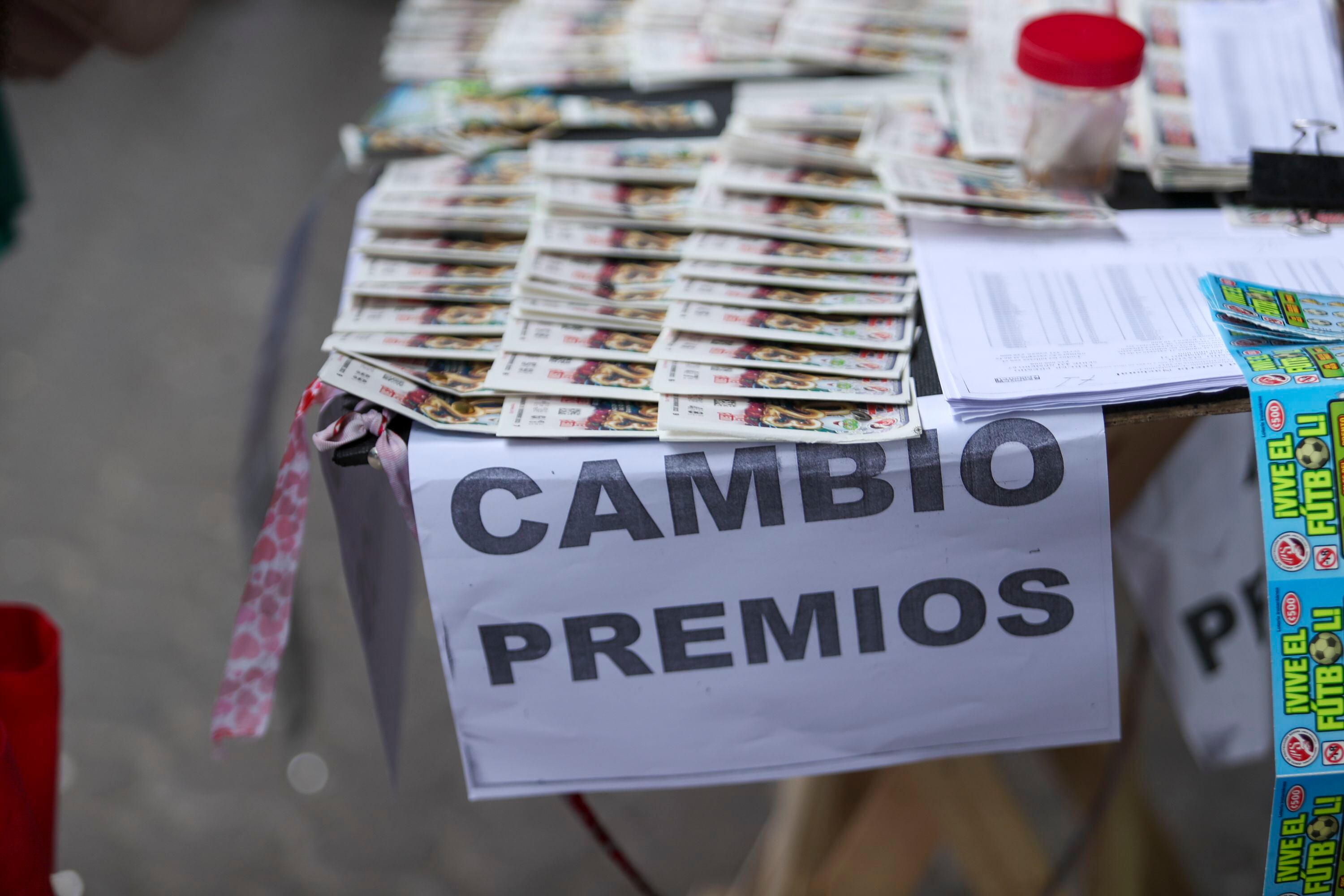 Mesa con boletos de lotería navideña y un letrero de "Cambio de premios", destacando los sorteos de consolación en Costa Rica.