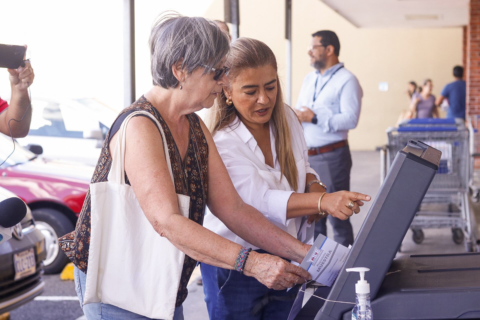 20/01/2024. Mayela Jiménez Vega (de lentes), de 74 años, fue la primera que simuló el voto electrónico en Sabanilla, este sábado 2 de enero, guiada por una funcionaria del TSE. Foto: Lilly Arce.