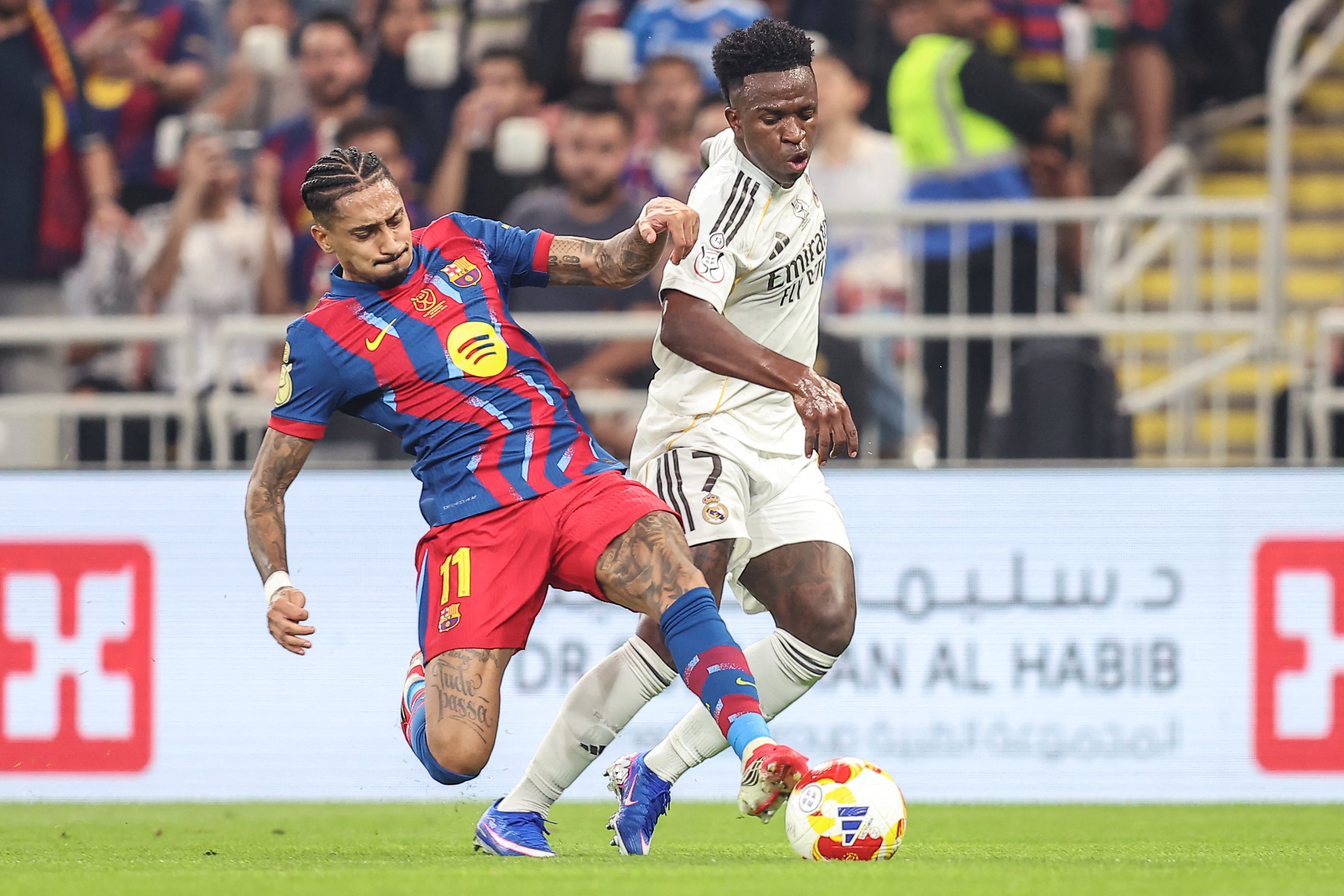 El delantero brasileño del Barcelona #11 Raphinha (izq.) y el delantero brasileño del Real Madrid #07 Vinicius Junior disputan el balón durante la final de la Supercopa de España entre el FC Barcelona y el Real Madrid en el estadio King Abdullah, en Yeda, el 11 de enero de 2026. (Foto: Haitham AL-SHUKAIRI / AFP)
