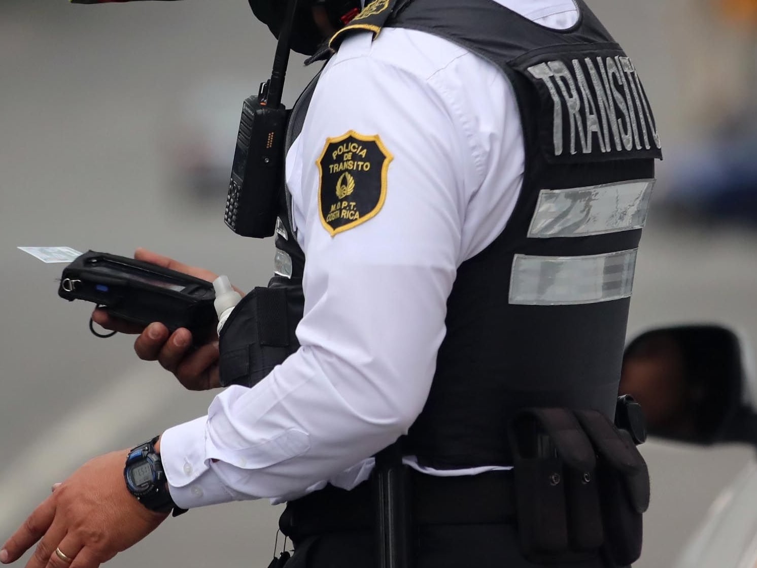 Oficial de la Policía de Tránsito en Costa Rica verifica documentos de un conductor detenido en un operativo de control en carretera.