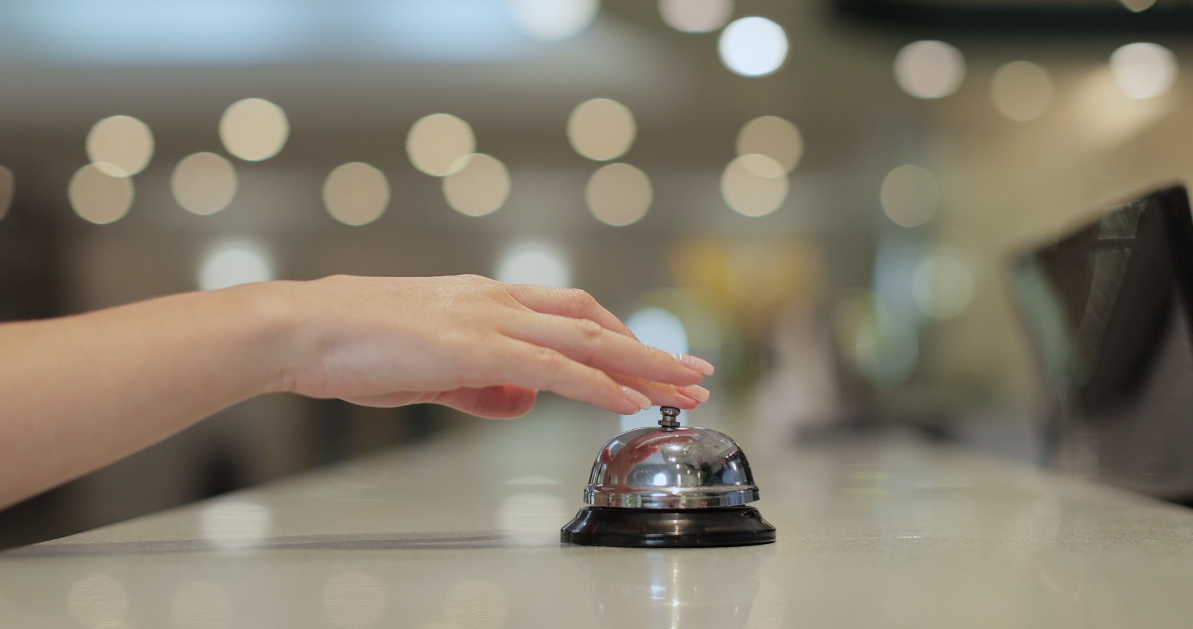 Mano presionando timbre en recepción de hotel, símbolo del crecimiento de la inversión hotelera y turismo en Costa Rica