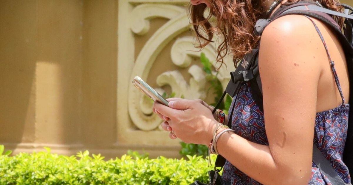 En la imagen una mujer utilizando un celular