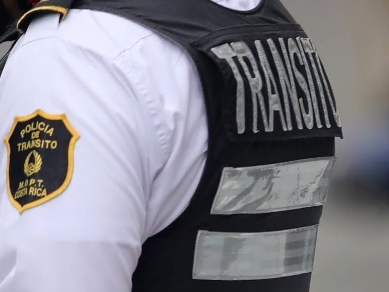 Oficial de la Policía de Tránsito en Costa Rica verifica documentos de un conductor detenido en un operativo de control en carretera.