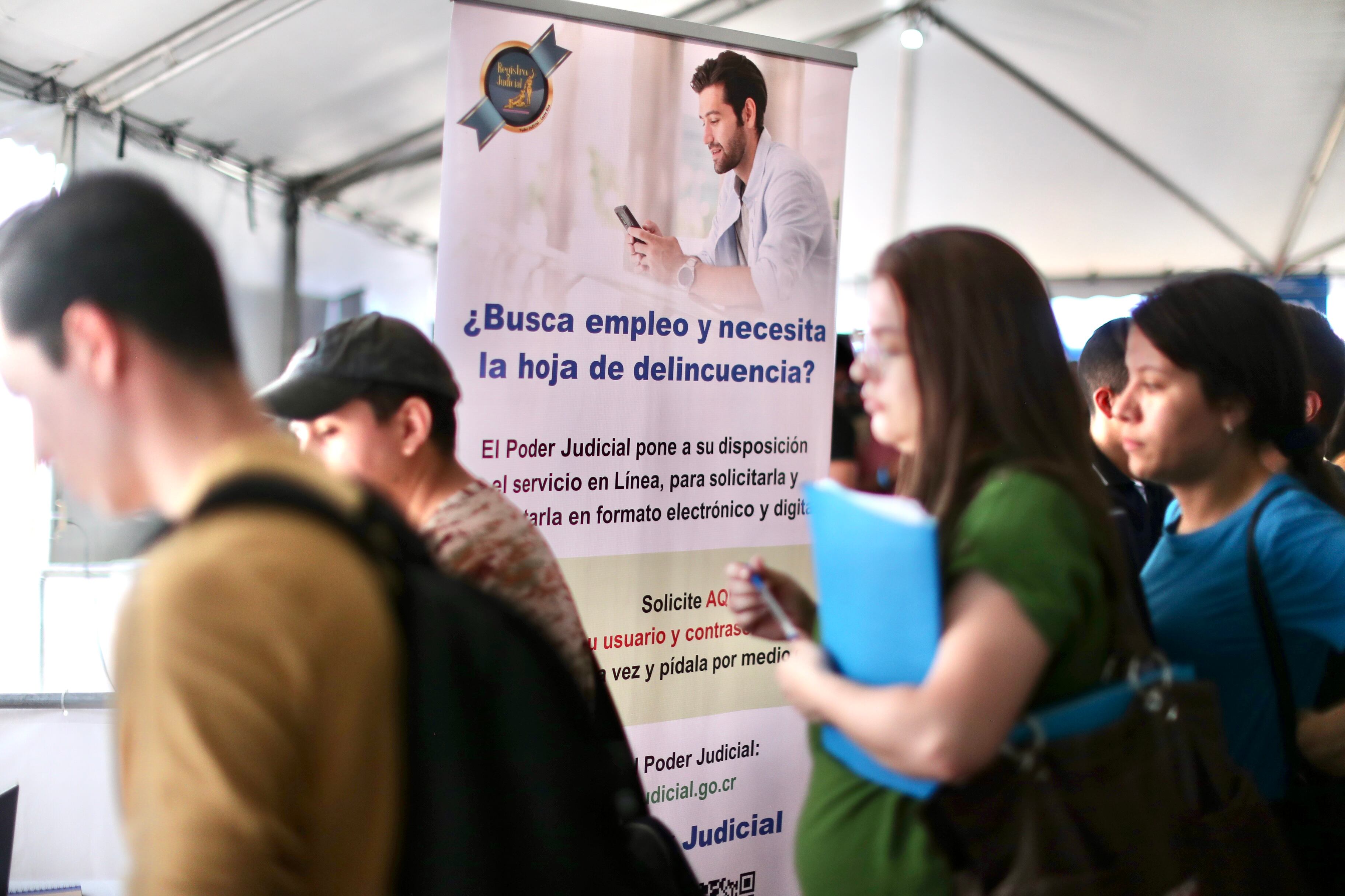 Asistentes a una feria de empleo realizan trámites y buscan oportunidades laborales mientras revisan información sobre la gestión de la hoja de delincuencia.