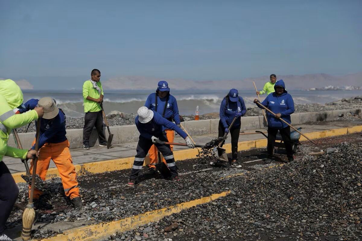 Un grupo de trabajadores hace limpieza de escombros en calles.