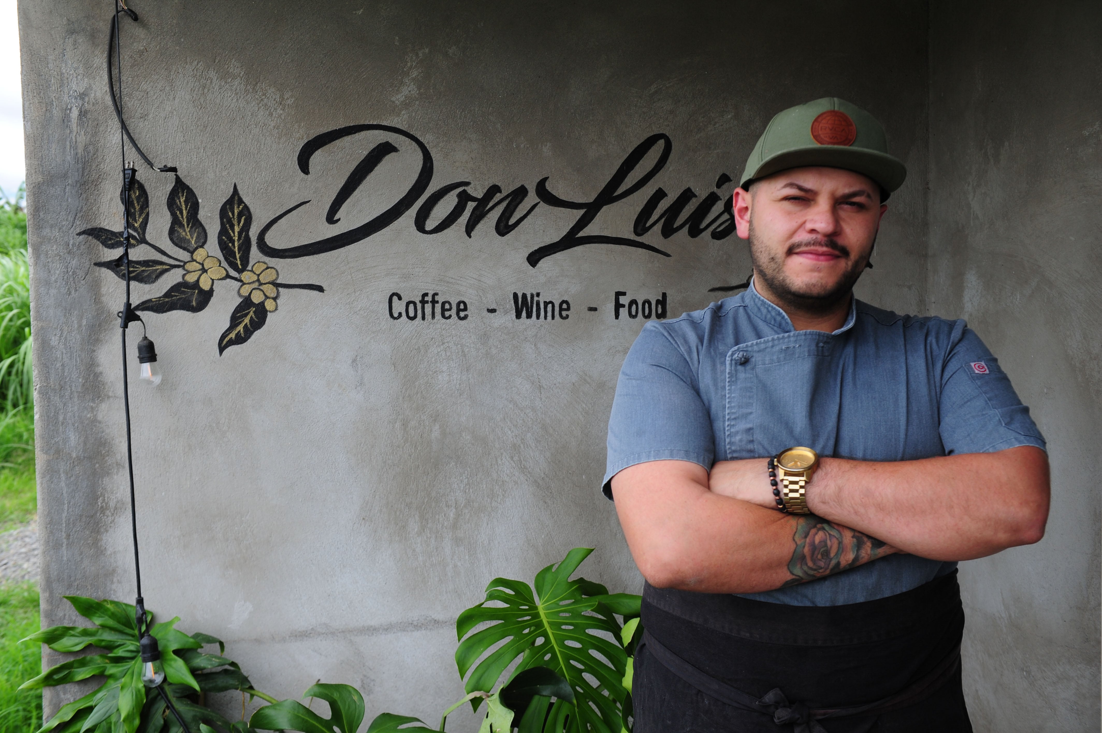 Chef Esteban Cordero posando con uniforme frente a la entrada de su restaurante Don Luis, con logo visible en la pared.