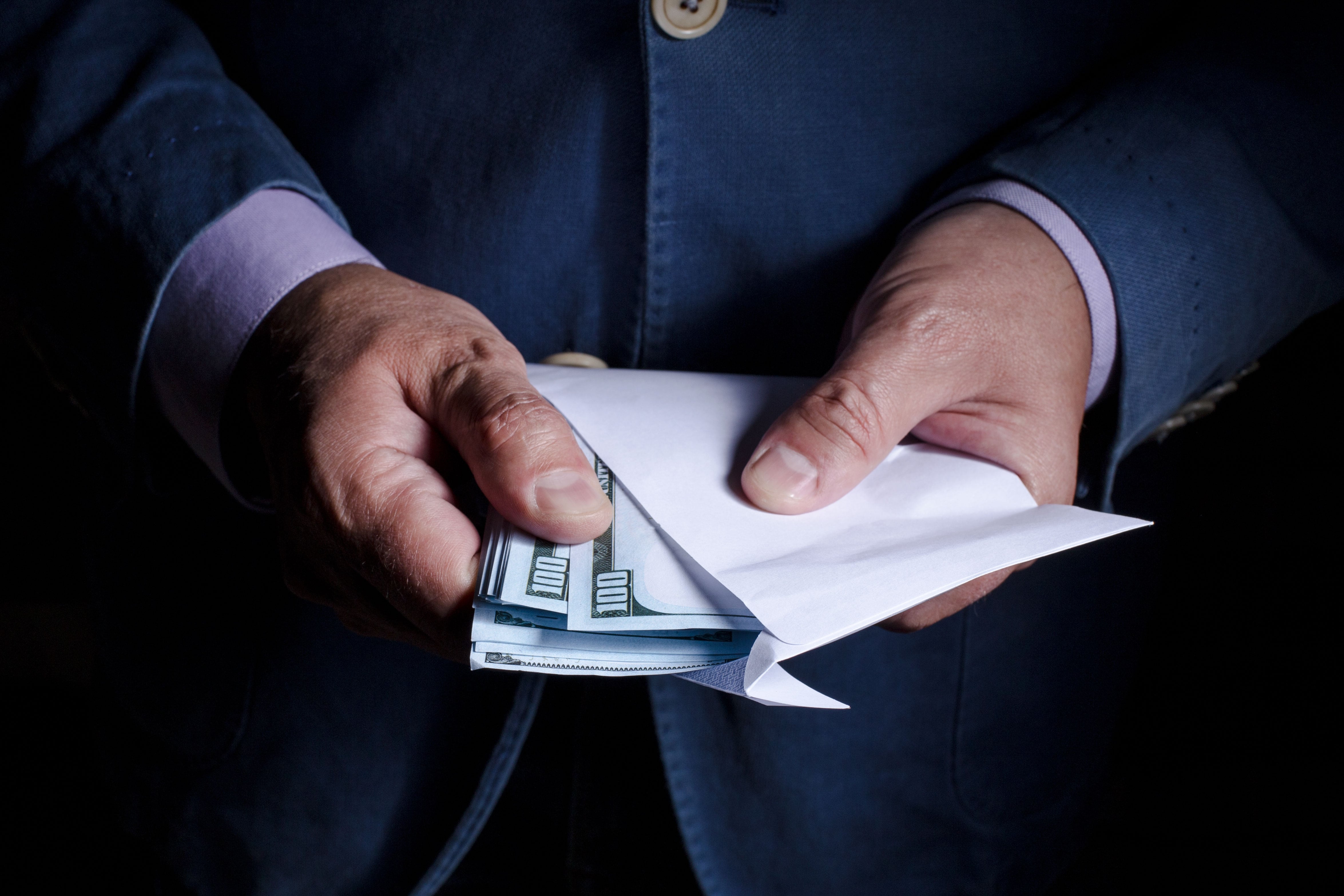 Una persona sostiene un sobre de dinero con dólares.