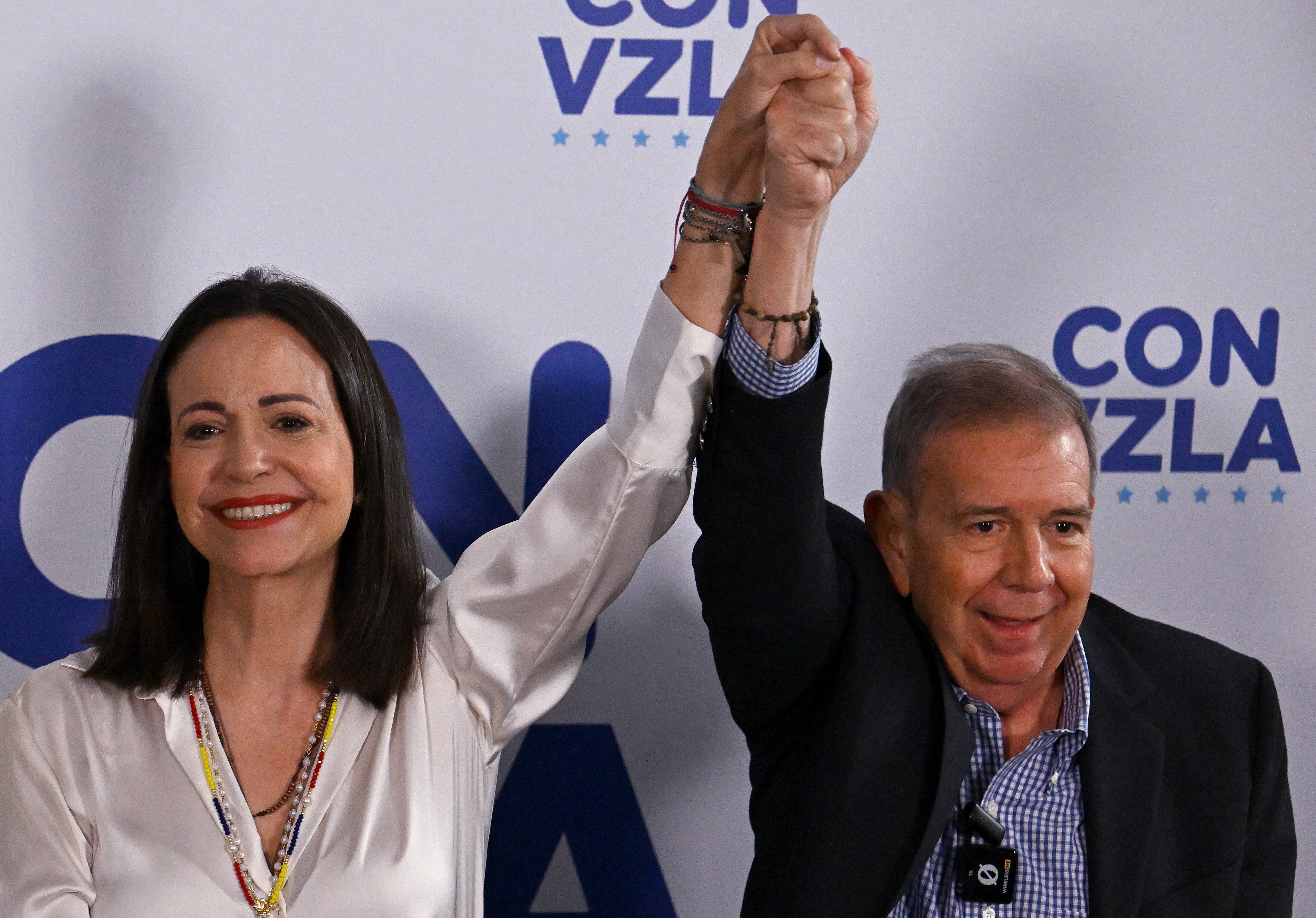 La líder opositora venezolana María Corina Machado se toma de la mano del candidato presidencial opositor Edmundo González Urrutia, en Caracas, Venezuela. Este lunes brindaron una conferencia de prensa al mismo tiempo en el que algunas zonas del país vivían en medio de las protestas. Foto: AFP