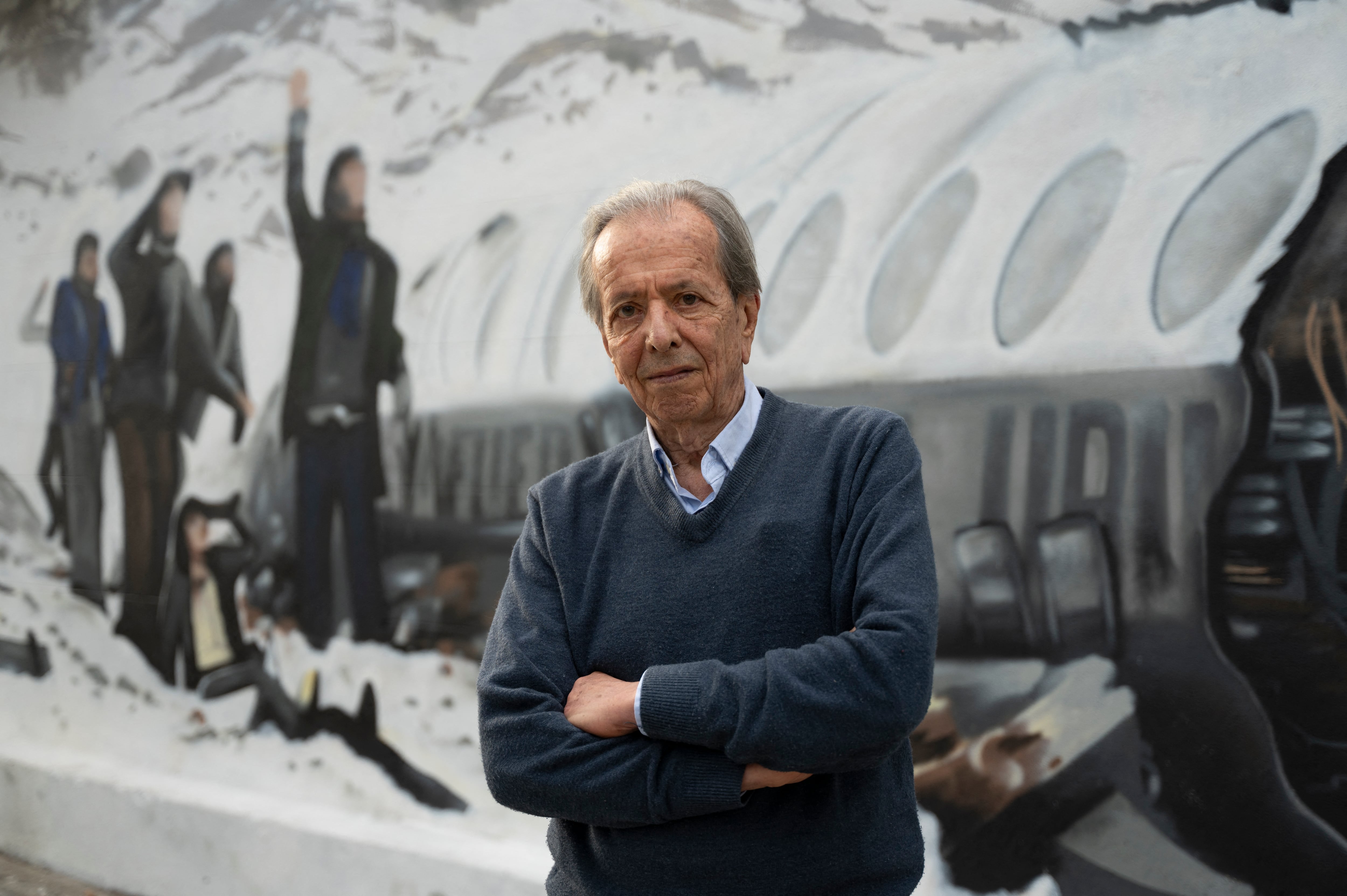 (FILES) Daniel Fernandez, one of the sixteen survivors of the plane crash of Uruguayan Air Force Flight 571 in the Andes Mountains on October 13, 1972, poses in front of a mural made by Graff Express depicting the accident in Montevideo, on November 15, 2023. Daniel Fernandez, 79, died on May 8, 2025, in Montevideo. (Photo by Eitan ABRAMOVICH / AFP)
