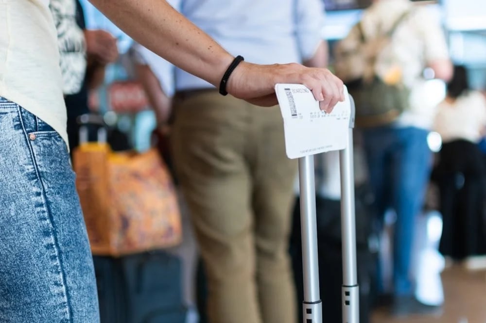 Viajero con su tarjeta de embarque en la mano mientras espera en la fila del aeropuerto.
