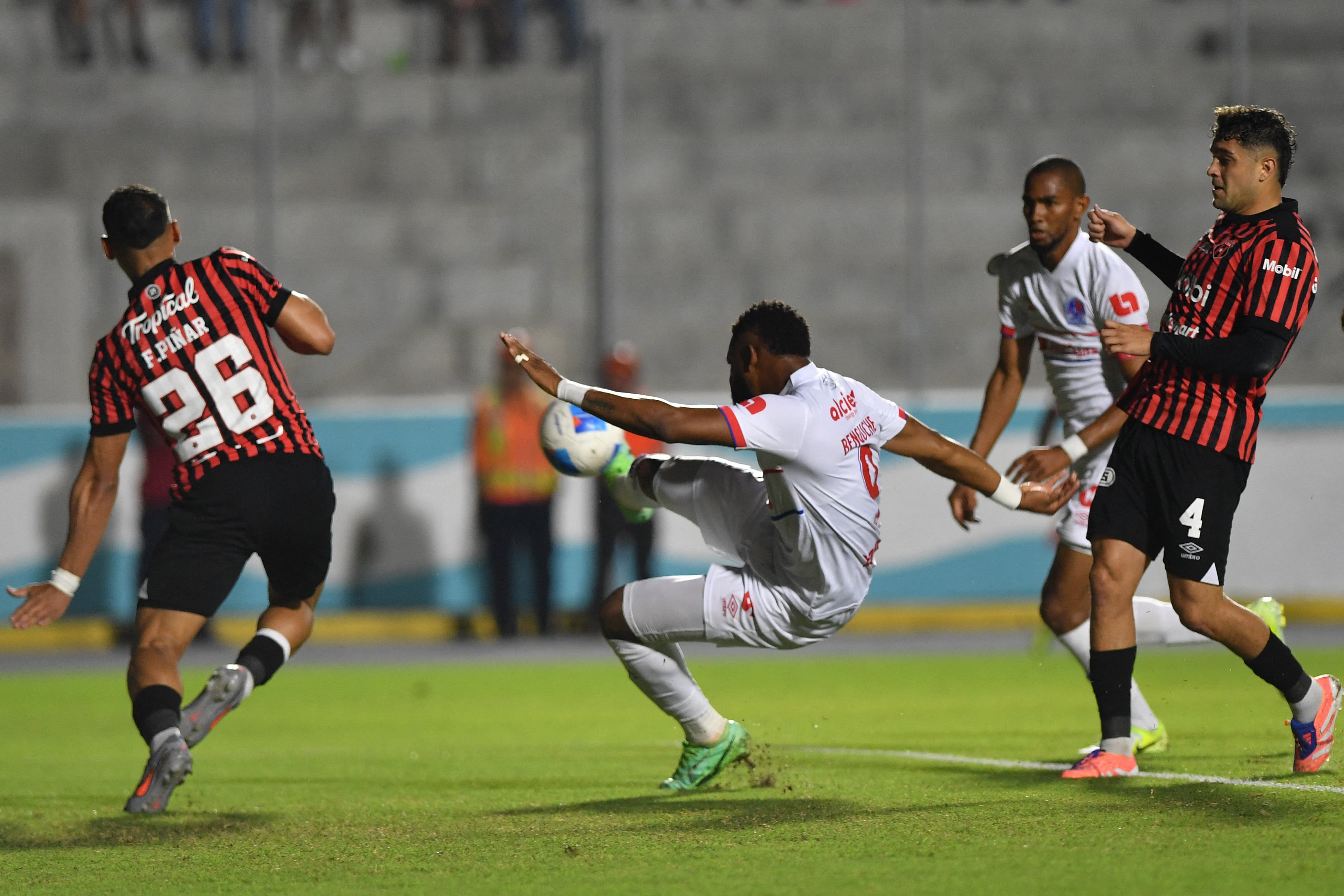 Alajuelense's defender #26 Fernando Pinar and Olimpia's forward #09 Jorge Benguche fight for the ball during the second leg of the CONCACAF Central American Cup semifinal football match between Honduras's Olimpia and Costa Rica's Alajuelense at the National Stadium Jose de la Paz Herrera in Tegucigalpa on October 30, 2025. (Photo by Orlando SIERRA / AFP)