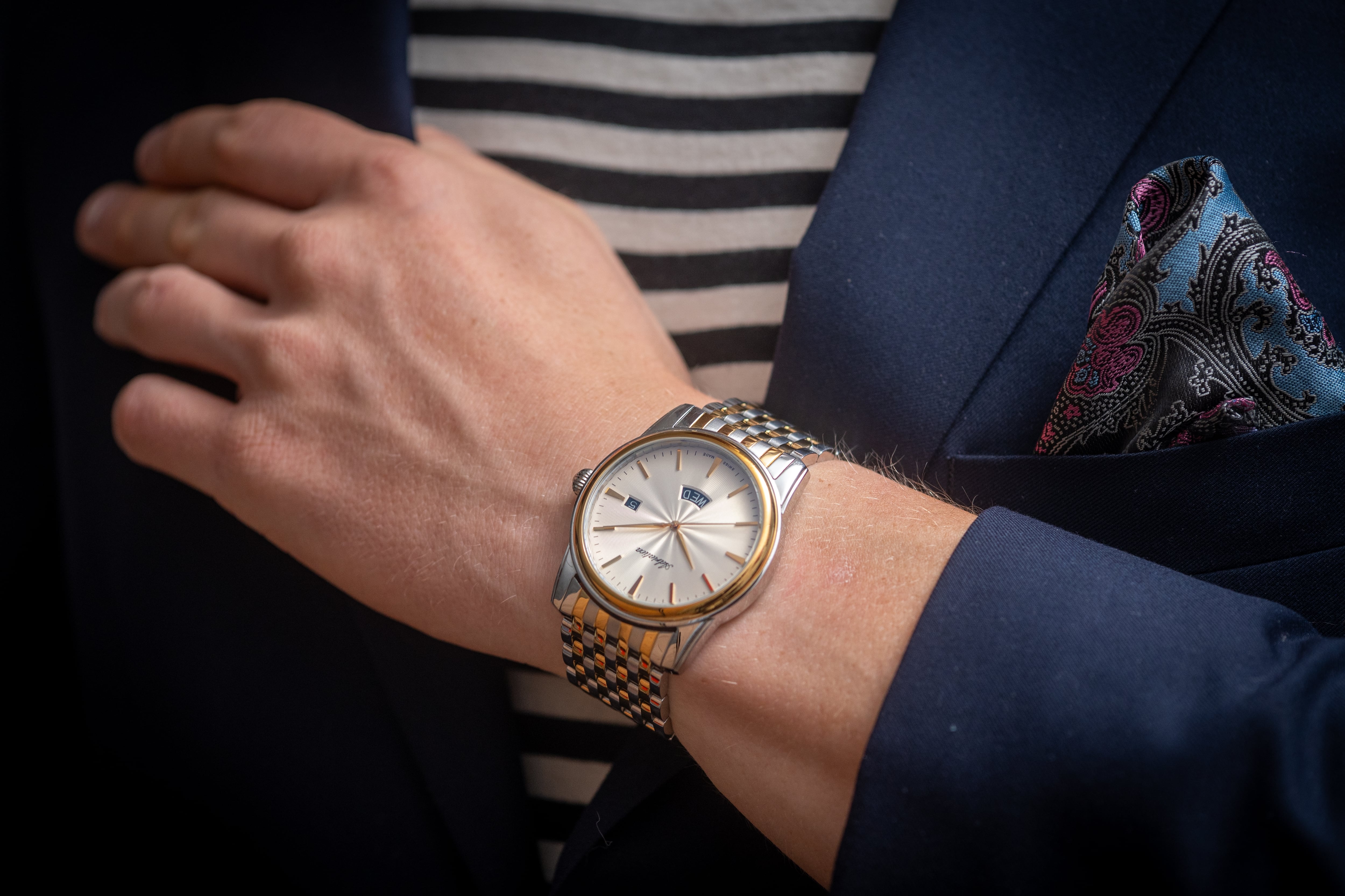 Primer plano de brazo de hombre con reloj fino, de marca, de pulsera de oro y plata.