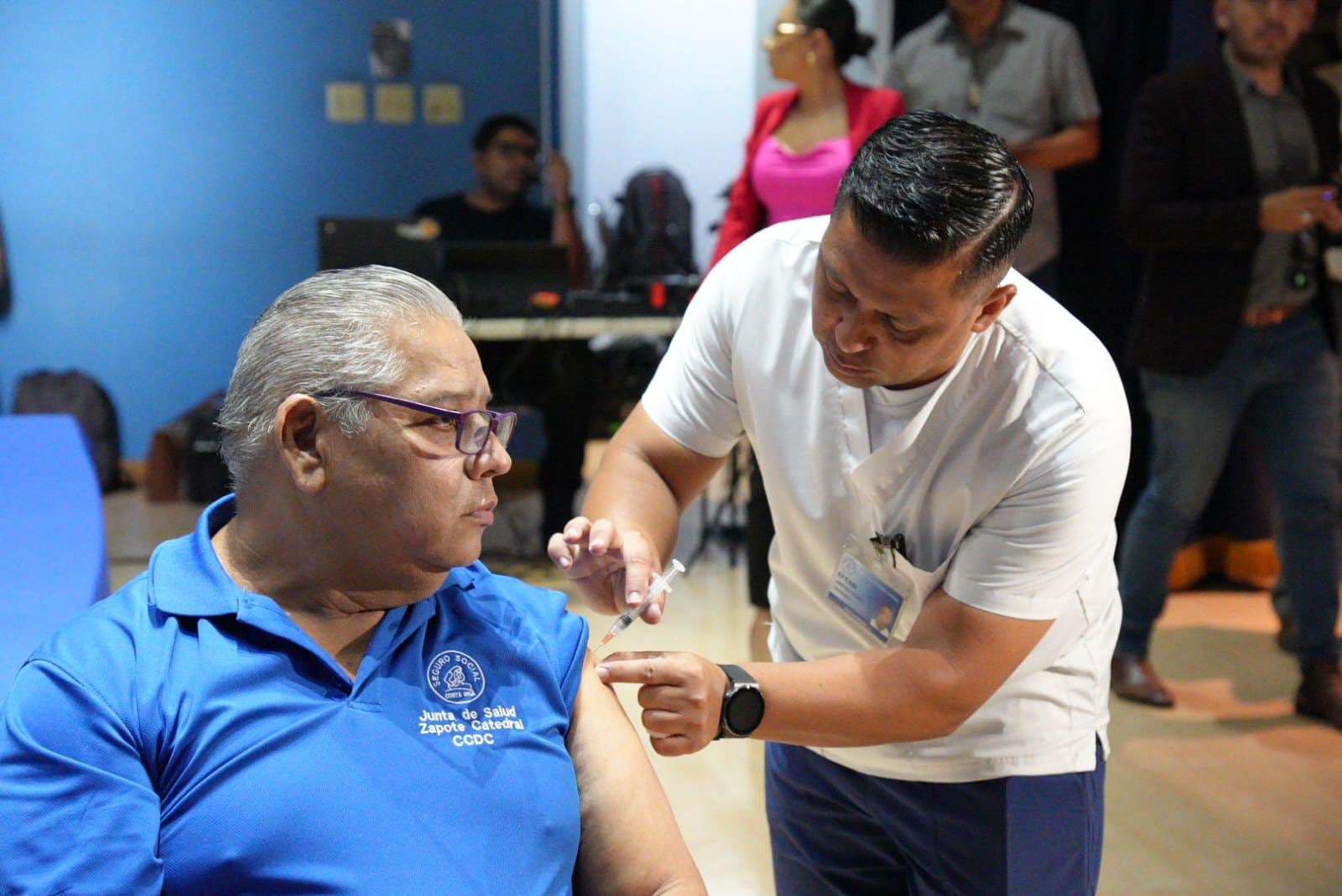 Un trabajador de la salud es vacunado contra la influenza por uno de sus compañeros.