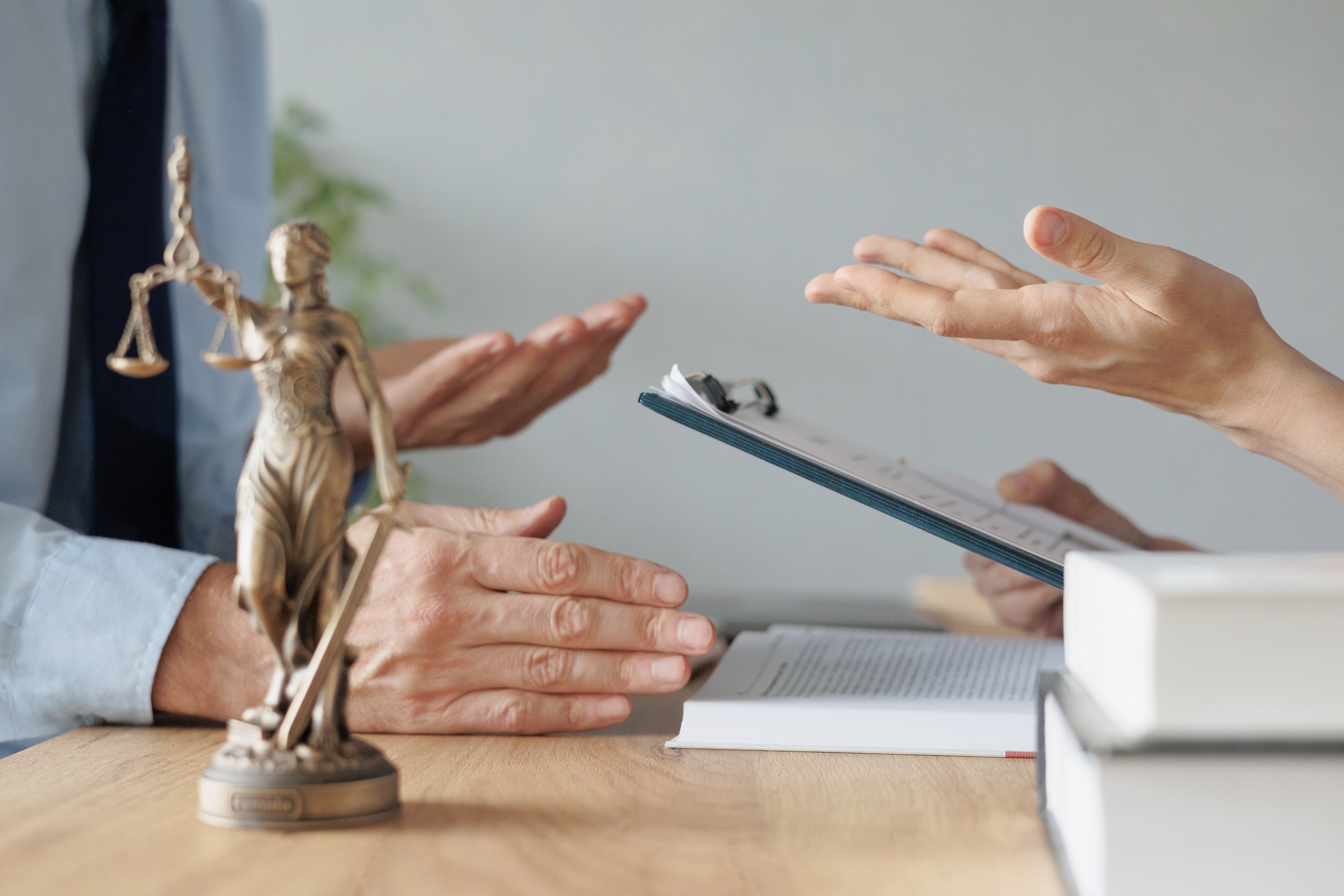 Figura de la justicia y manos de personas en negociaciones legales para llegar a acuerdos.
