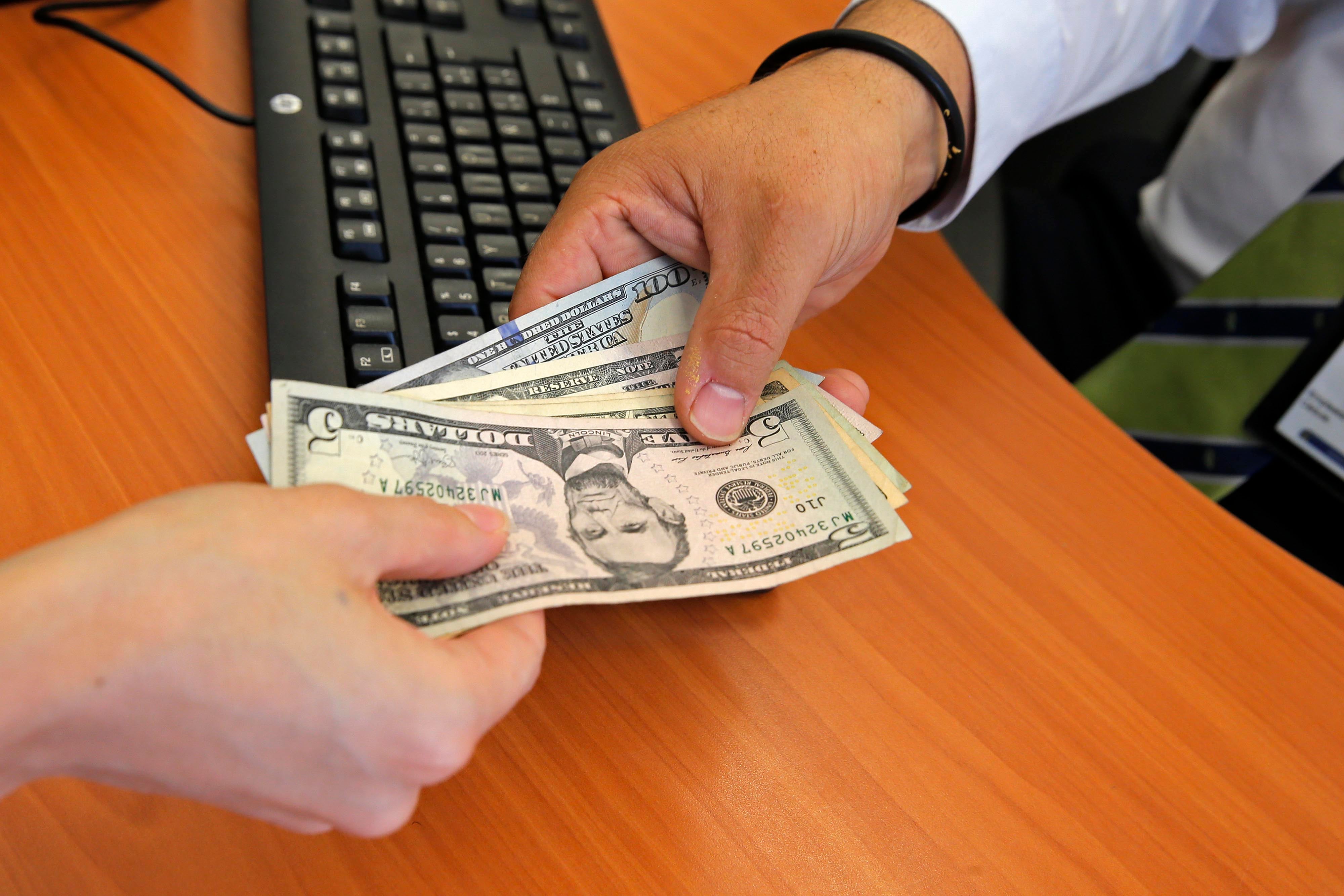 Una persona recibe dólares en un banco.