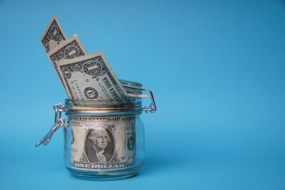 Billetes de un dólar en un frasco de vidrio, representando el ahorro en certificados de depósito a plazo en dólares en Costa Rica.