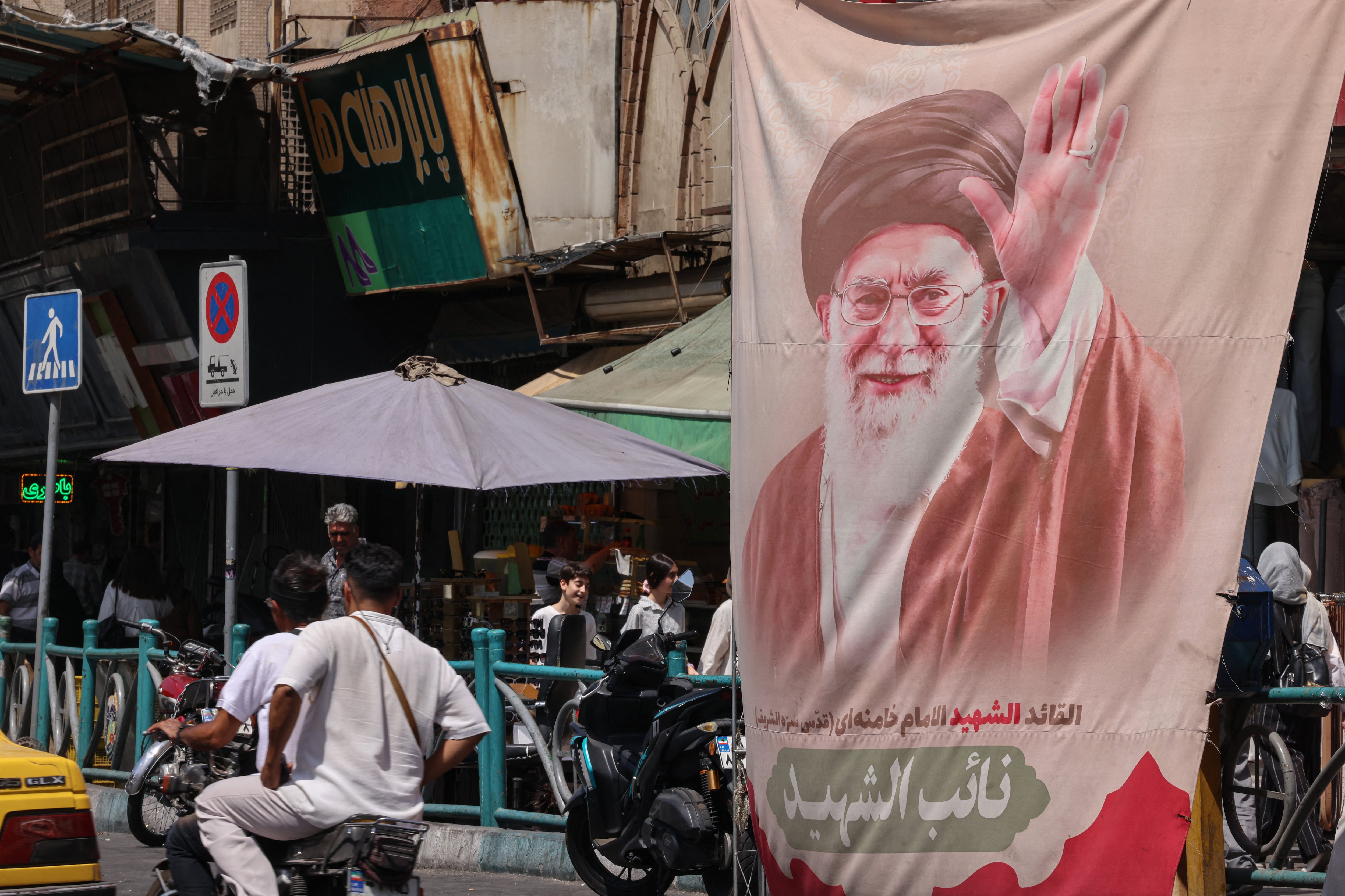 El 19 de julio de 2026, ciudadanos iraníes pasaron junto a una pancarta con la imagen del líder supremo asesinado de Irán, el ayatolá Ali Khamenei, en la plaza Valiasr de Teherán. Estados Unidos afirmó que los ataques aéreos del 19 de julio tenían como objetivo "castigar" a Irán por las primeras muertes de militares estadounidenses desde la reanudación de las hostilidades con la república islámica.