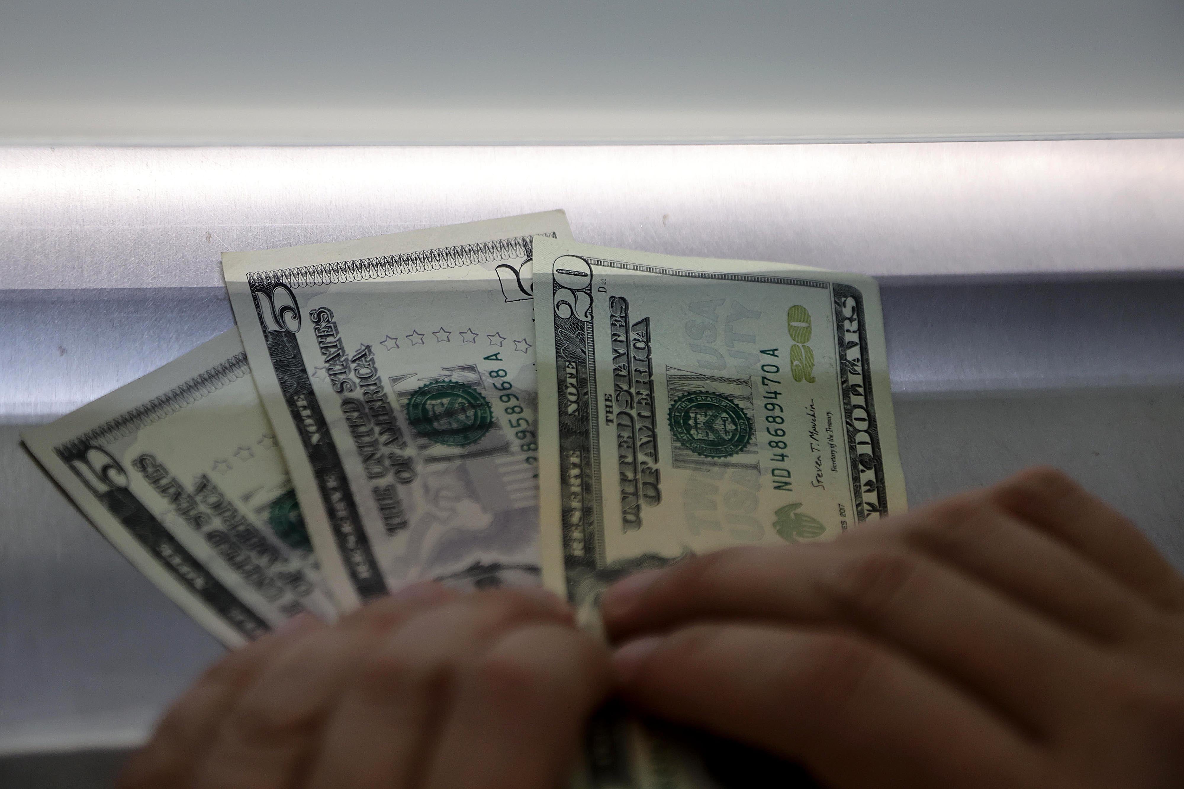 Primer plano de billetes de dólares en una ventanilla de intermediario cambiario en Costa Rica, en el contexto de la caída del tipo de cambio por debajo de ¢500 en marzo de 2025.