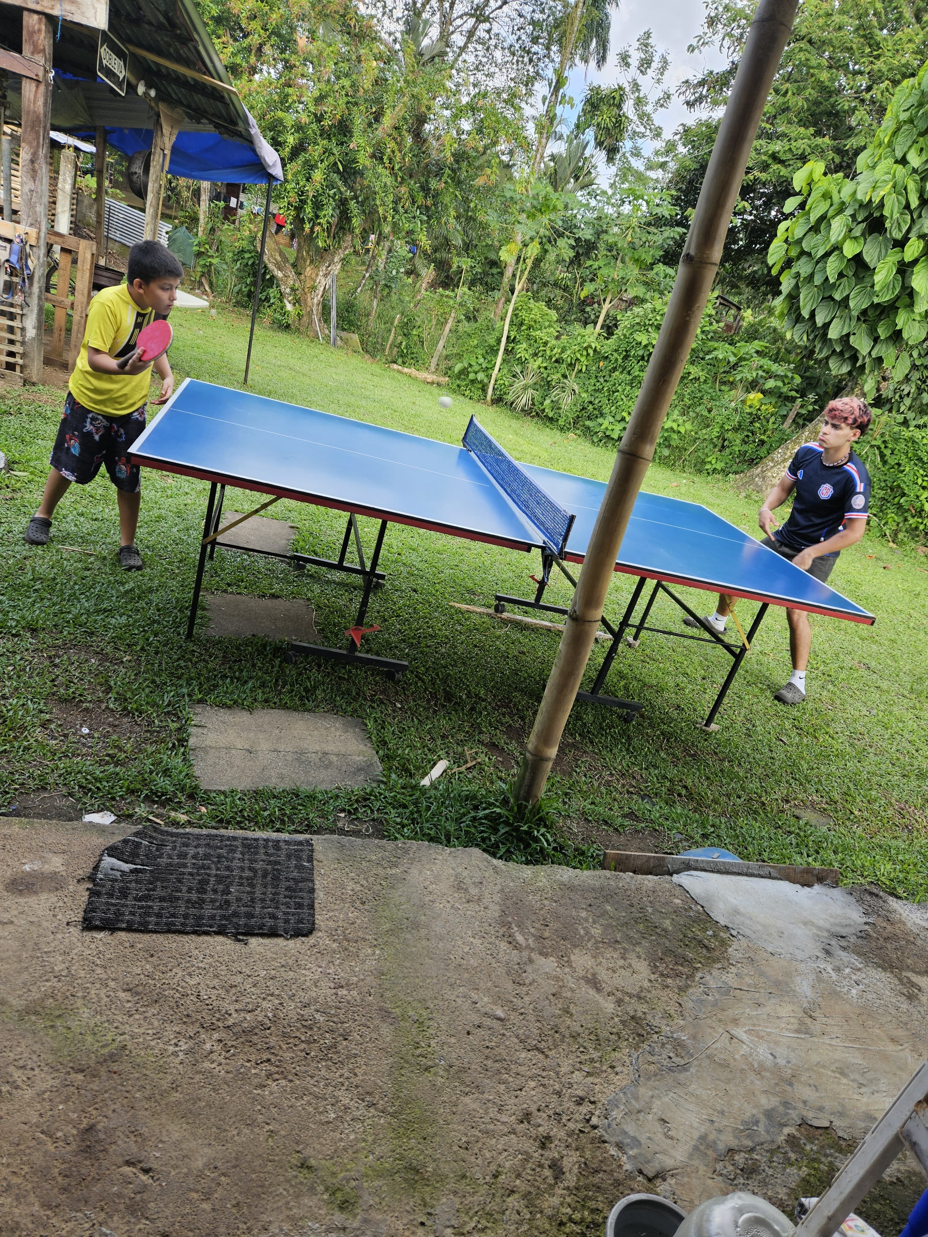 Matteus y su hermano jugando tenis de mesa en su casa