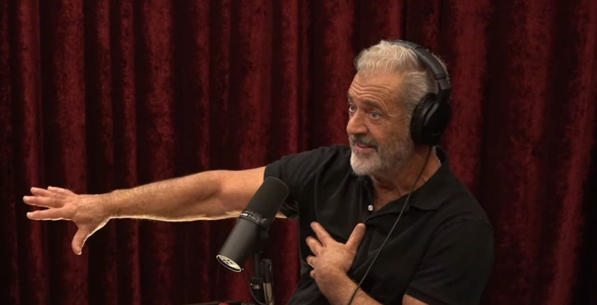 Mel Gibson en el podcast de Joe Rogan con audífonos y frente a un micrófono