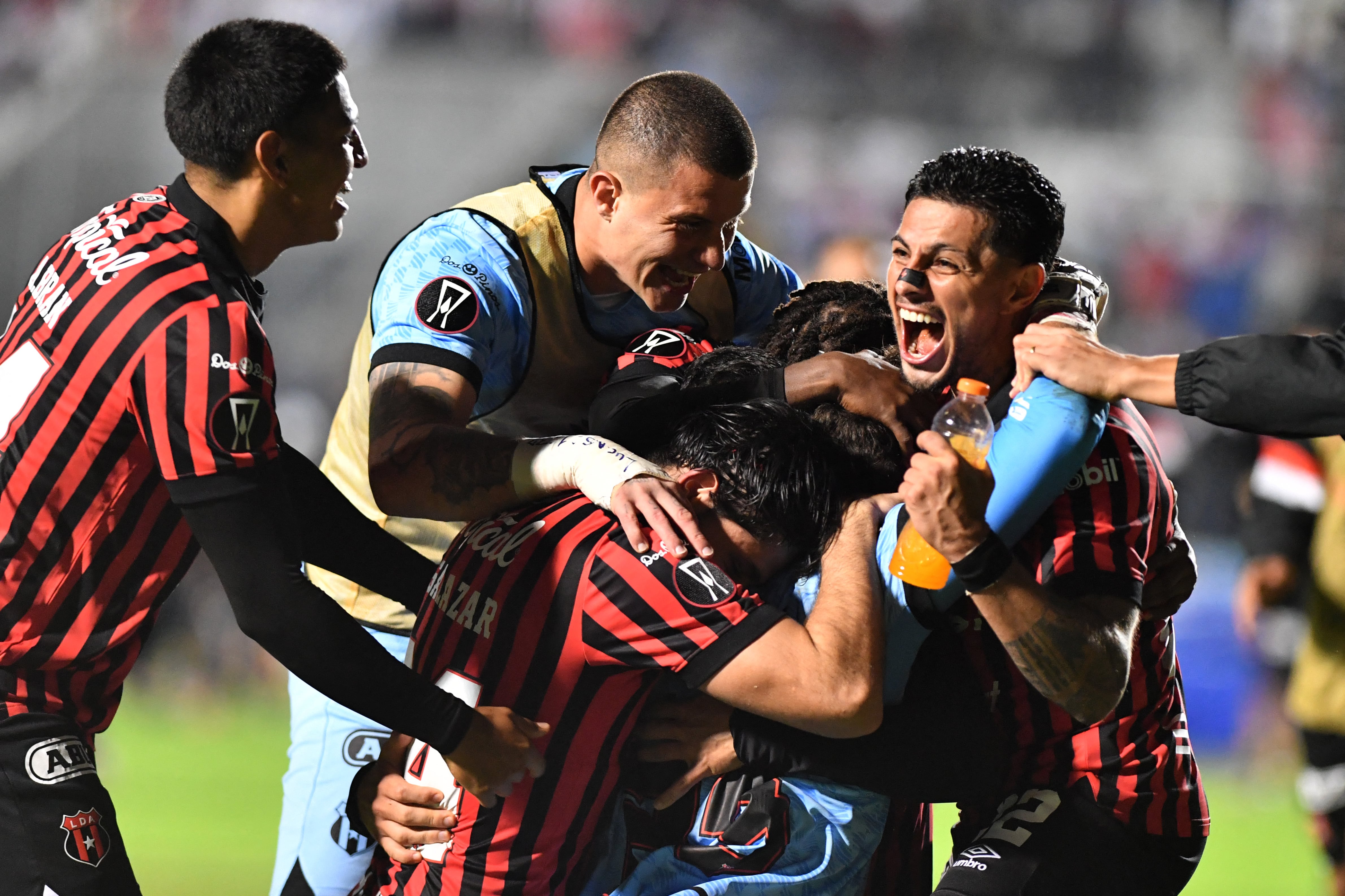 Alajuelense's Uruguayan goalkeeper #23 Washington Ortega (C) celebrates with teammates after winning the penalty shootout and the second leg of the CONCACAF Central American Cup semifinal football match between Honduras's Olimpia and Costa Rica's Alajuelense at the National Stadium Jose de la Paz Herrera in Tegucigalpa on October 30, 2025. (Photo by Orlando SIERRA / AFP)